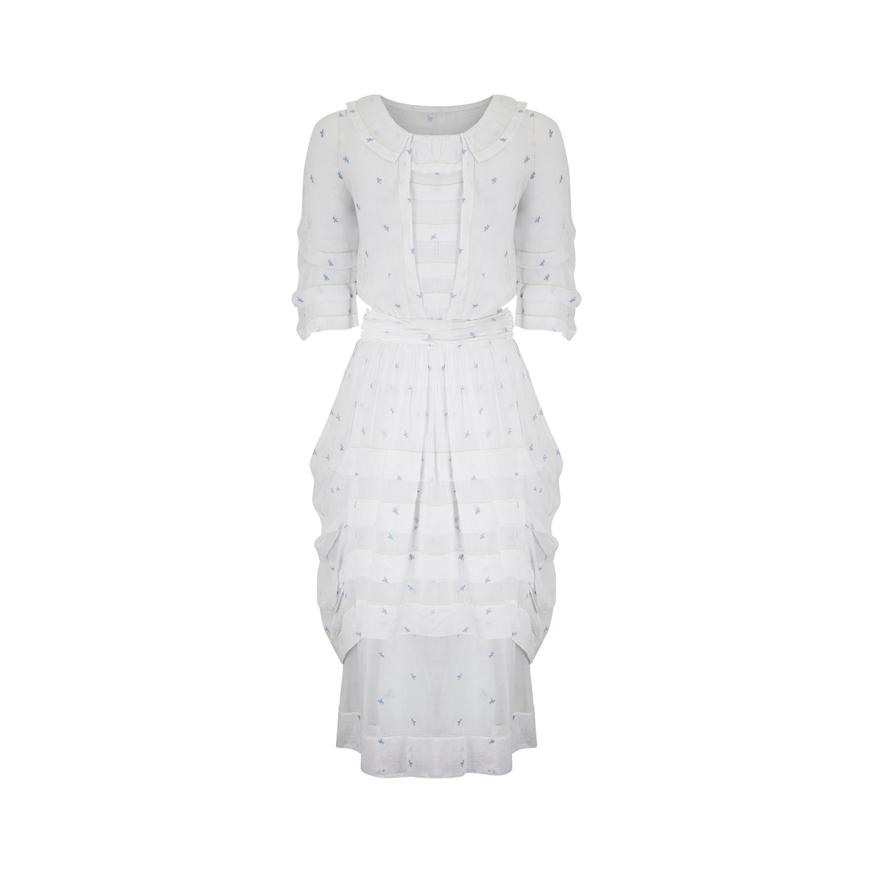 This is a superb example of an American made tea or lawn dress from the 1900s Edwardian era or possibly a tiny bit later.  The dress is made from a lightweight white muslin cotton and has been hand-embroidered all over with what looks like a little