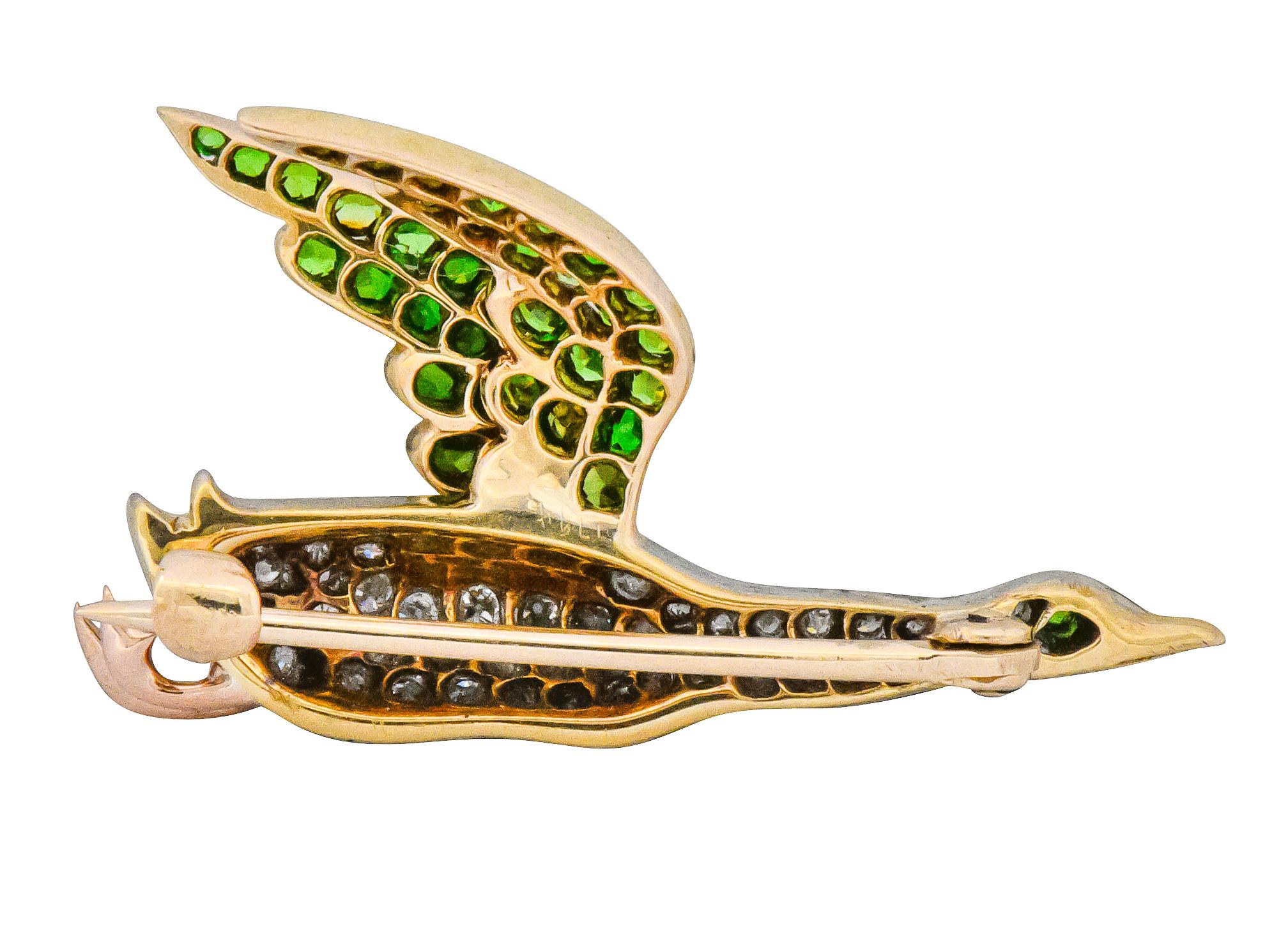 Brooch designed as goose in flight with gold wings including pavé set single cut and Swiss cut demantoid garnets weighing approximately 0.90 carat total, bright yellowish-green

Body of goose pavé set in platinum with old European cut diamonds