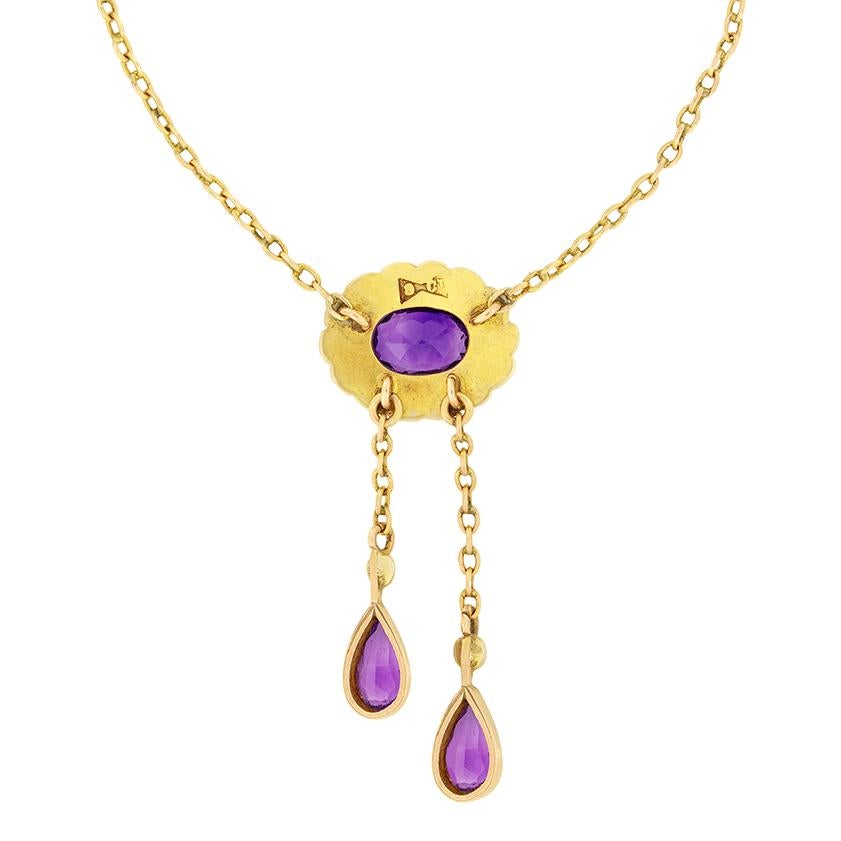 This charming amethyst and pearl necklace was crafted in the Edwardian period. At the centre a single rub over set amethyst is surrounded by a halo of pearls. The Amethyst is an oval cut stone weighing 1.00 carat. Two drop down amethysts add further