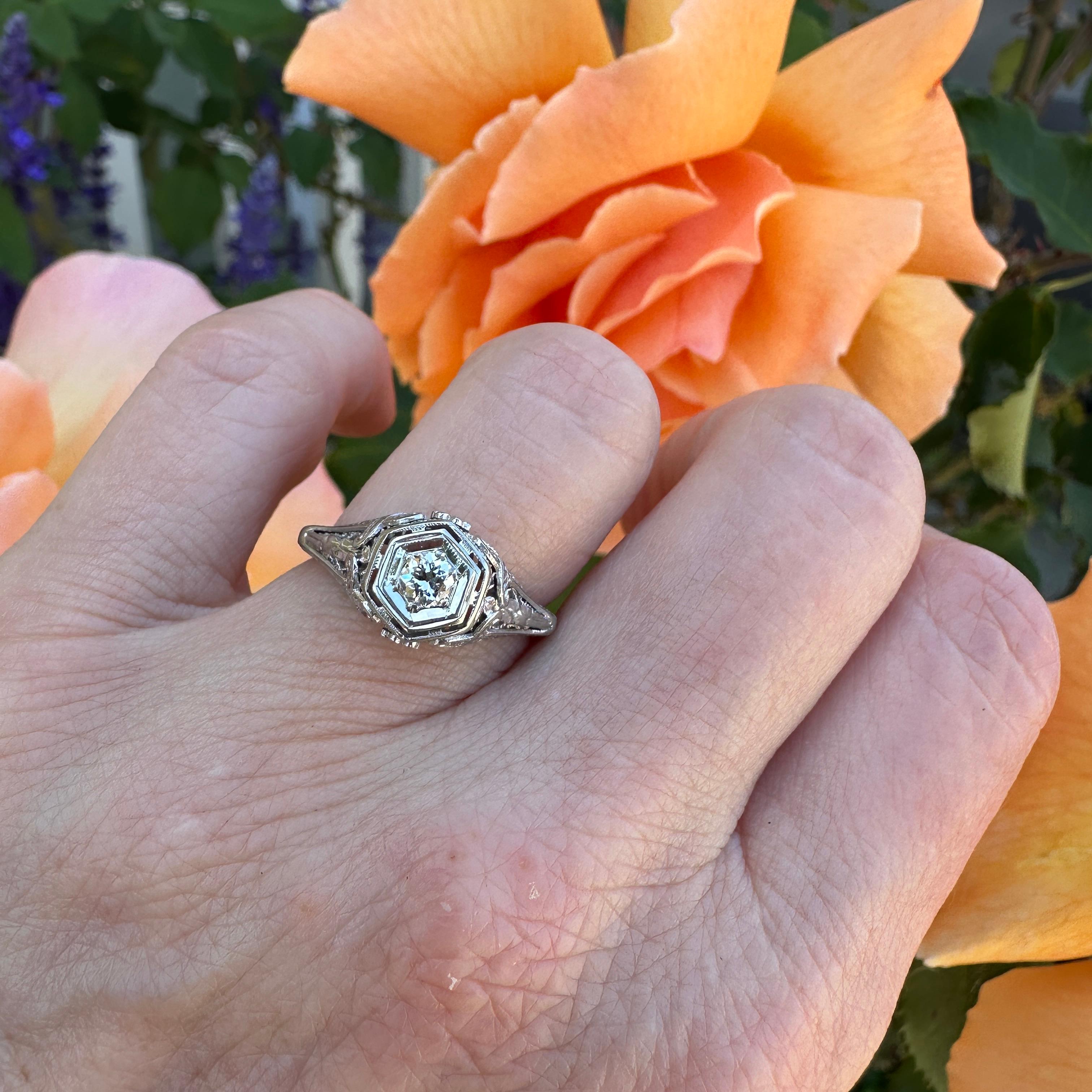 Details:
Super sweet Edwardian 18K white gold filigree .20 carat diamond ring from the Edwardian era, 1905-1915! Lovely and romantic! This ring features a lovely old European cut diamond. The fabulous filigree has beautiful sweet flowers, and