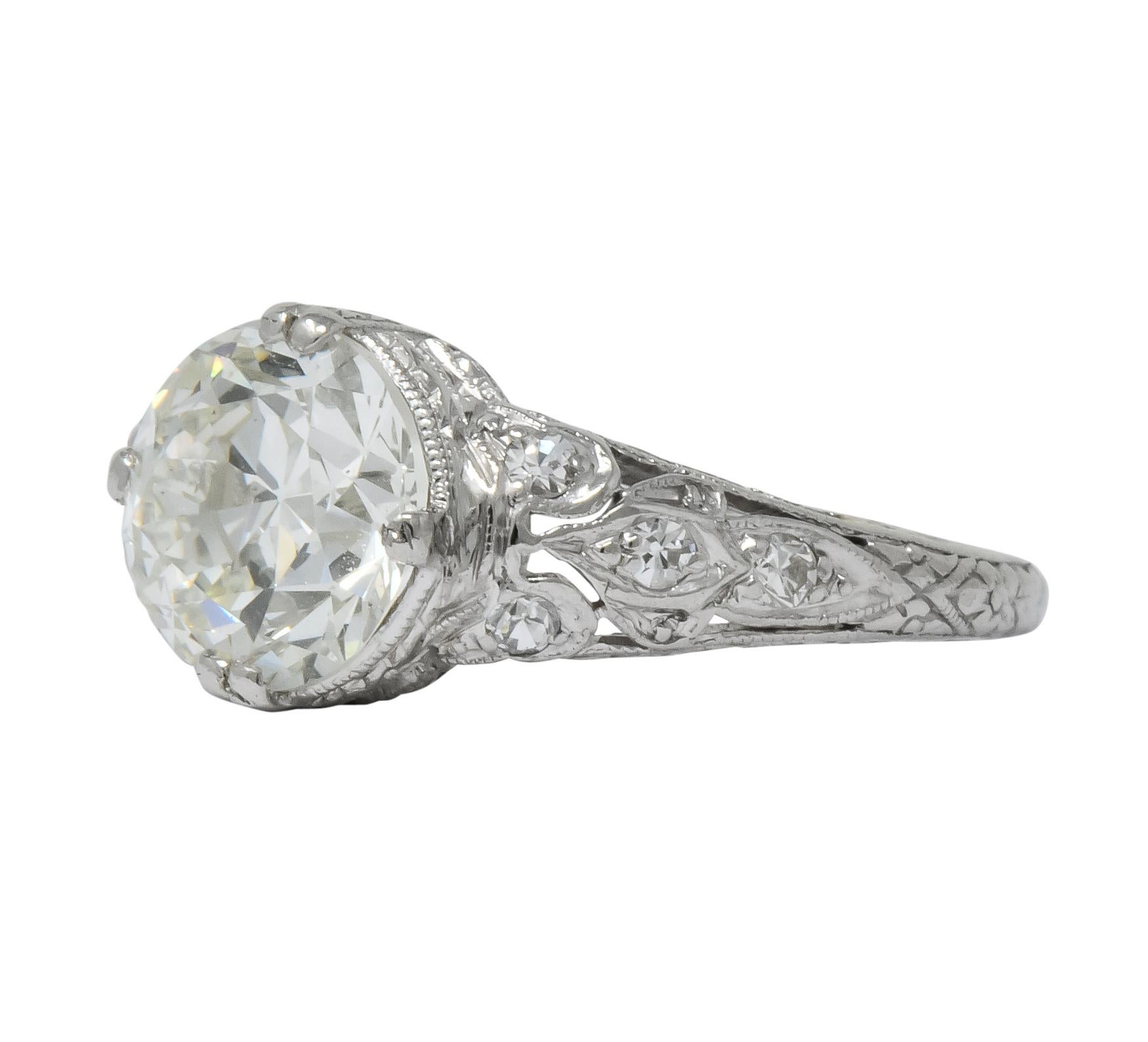 Centering an old European  circular brilliant cut diamond weighing 2.01 carats, J color and SI1 clarity

Accented by single cut diamonds weighing approximately 0.12 carat, eye-clean and white

Engraved foliate motif gallery and shank with millegrain