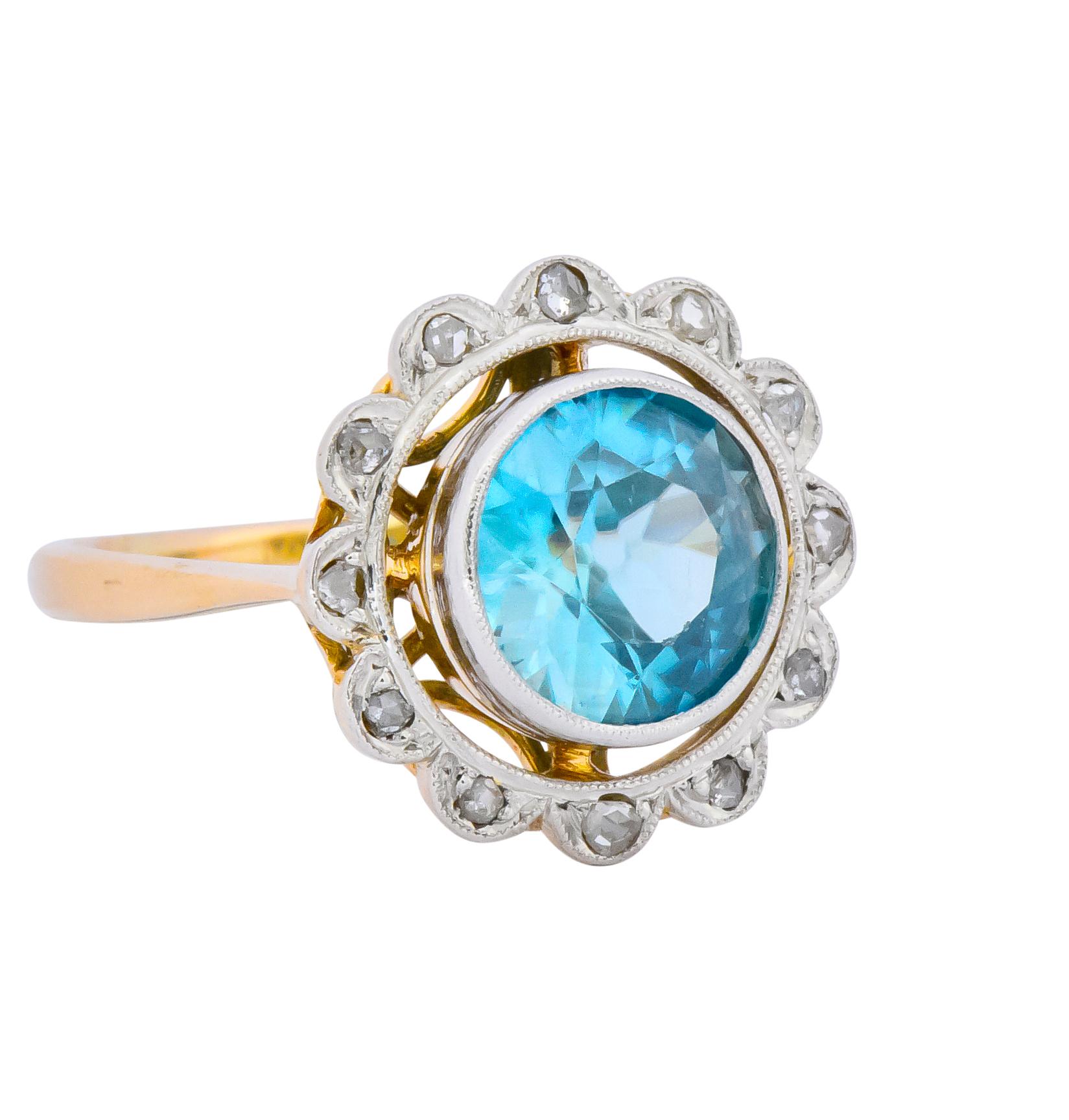 Centering a round cut bezel set zircon weighing approximately 2.20 carats, bright medium blue

With a delicate rose cut diamond halo

Platinum-topped with a pierced scrolling heart motif gallery

Tested as platinum and 14 karat gold

Ring Size: 5 &
