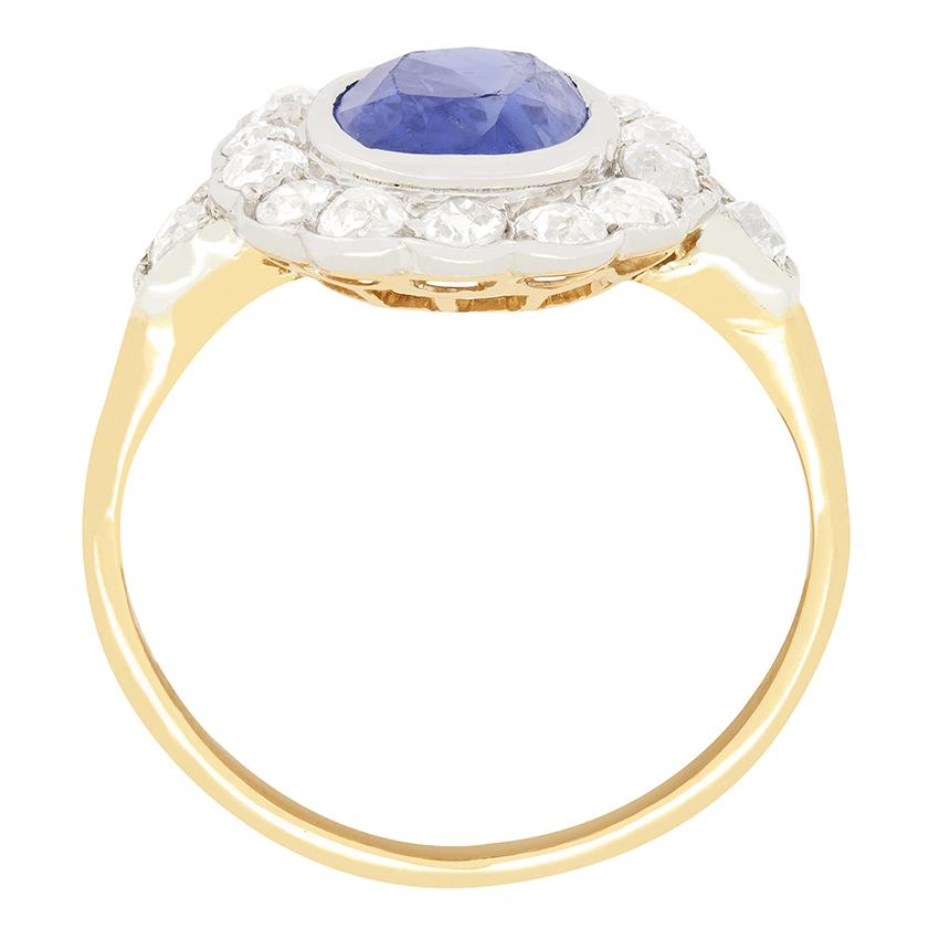 This exquisite Edwardian cluster ring features a stunning 2.20 carat old oval cut natural sapphire, securely rub over set int0 platinum. Surrounding the centrepiece are fourteen old cut diamonds with an additional diamond set onto each shoulder.