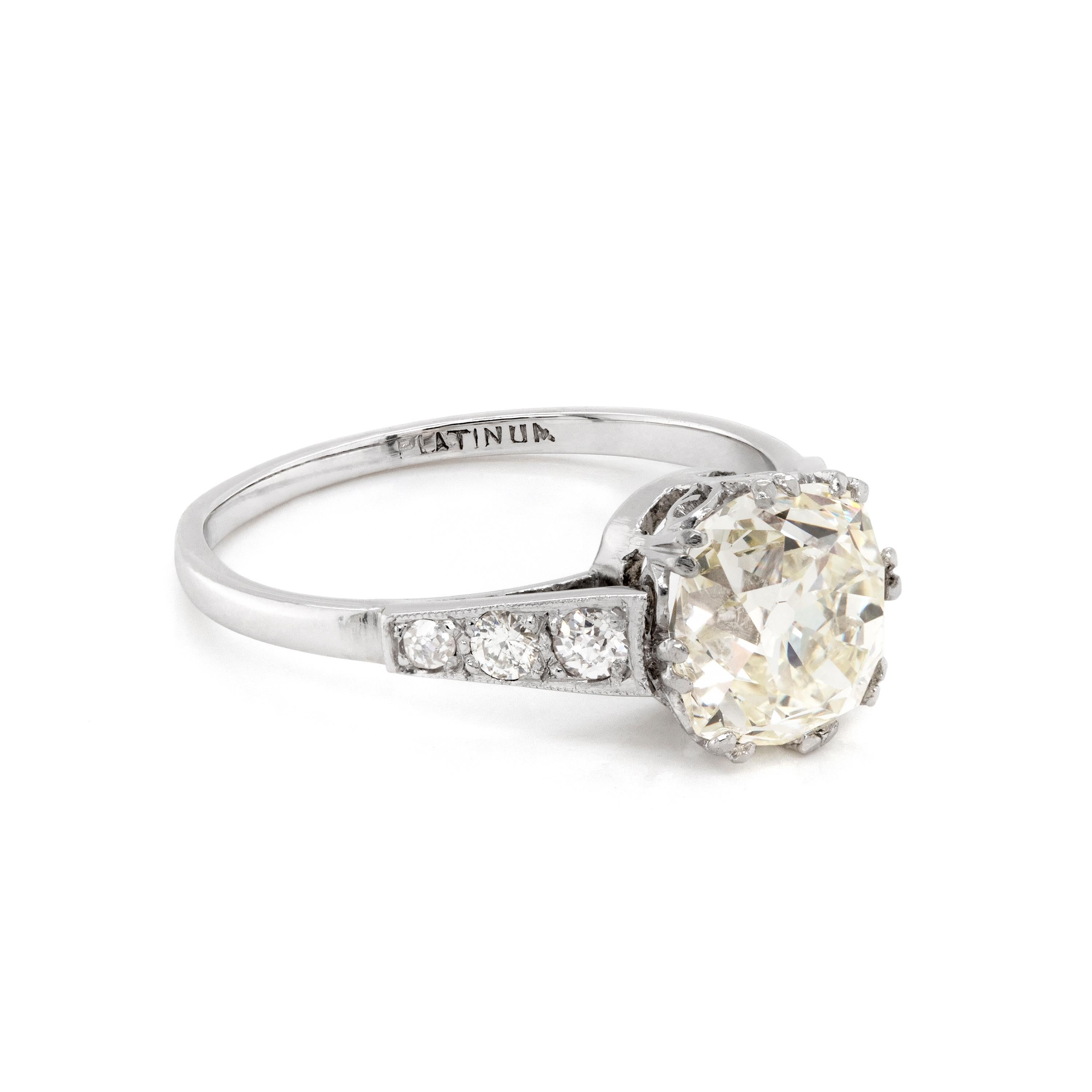 This original antique engagement ring features a beautiful old mine cushion cut diamond weighing 2.26ct set in an eight split claw, open back setting. The stone is wonderfully accompanied by three old cut diamonds on either shoulder, weighing an