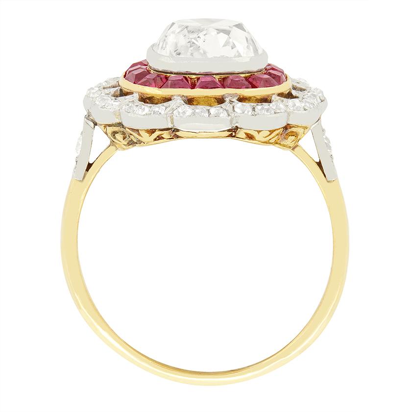A stunning 2.30 carat old cushion cut diamond is enveloped in a ring of rubies in this beautiful Edwardian target ring. The central diamond is of good quality with colour of F to G and clarity of SI2 and is rub over set within platinum.  The