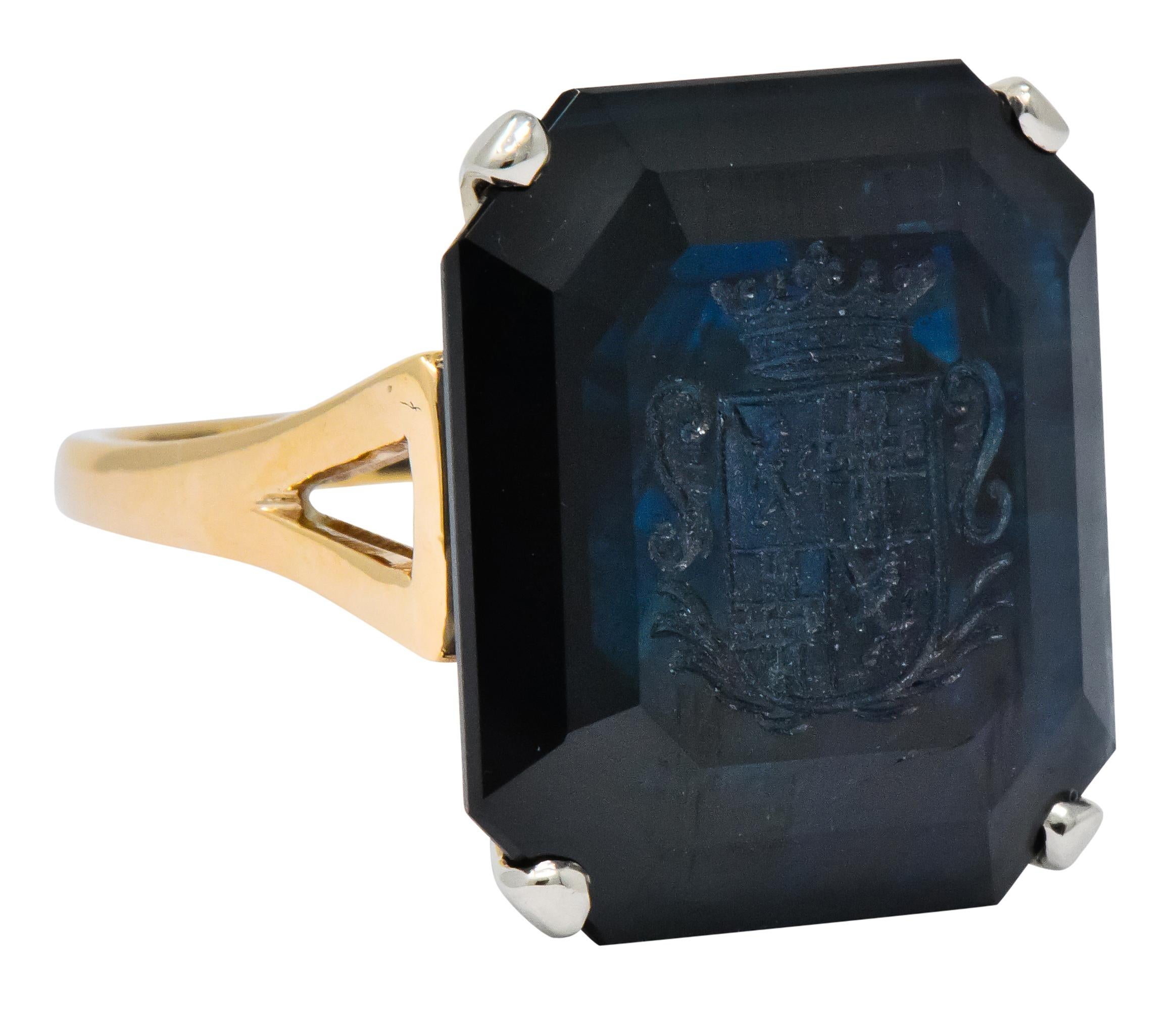 Centering an octagonal intaglio cut sapphire weighing 23.88 carats total, transparent and dark blue in color with no indication of heating

Deeply carved with coat of arms featuring lions, crosses, and scrollwork motif, all topped by a crown

Basket