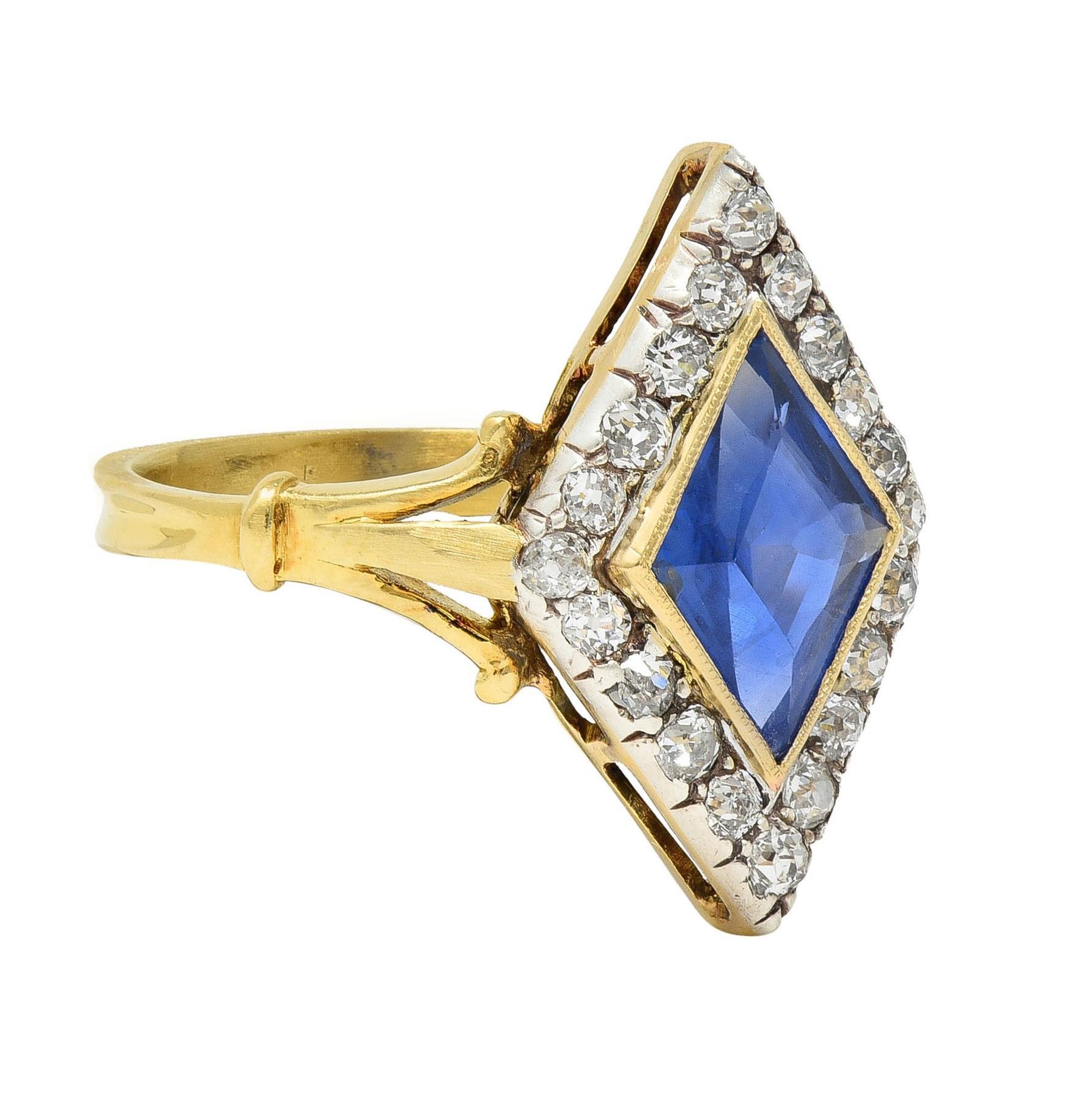 Centering a lozenge cut sapphire weighing approximately 1.80 carats - transparent medium blue in color 
Natural Sri Lankan (Ceylon) in origin and displaying no indications of heat treatment
Set in a gold bezel with a halo of old single cut diamonds