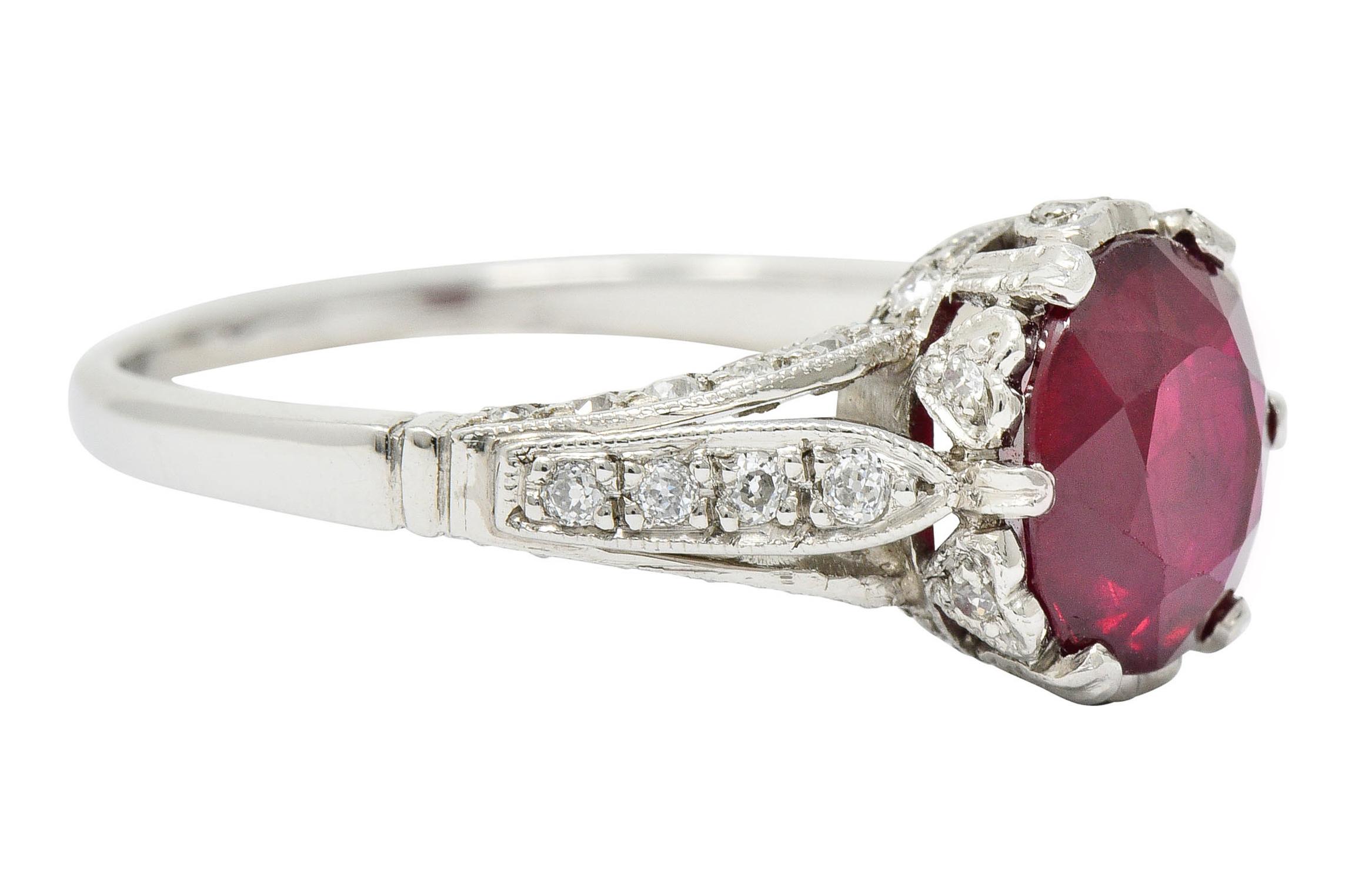 Centering an oval mixed cut Burma Ruby weighing 2.02 carats; vibrantly red in color

Set low in a stylized head featuring a heart motif and flanked by very slight cathedral shoulders

Accented throughout by old European cut diamonds weighing in