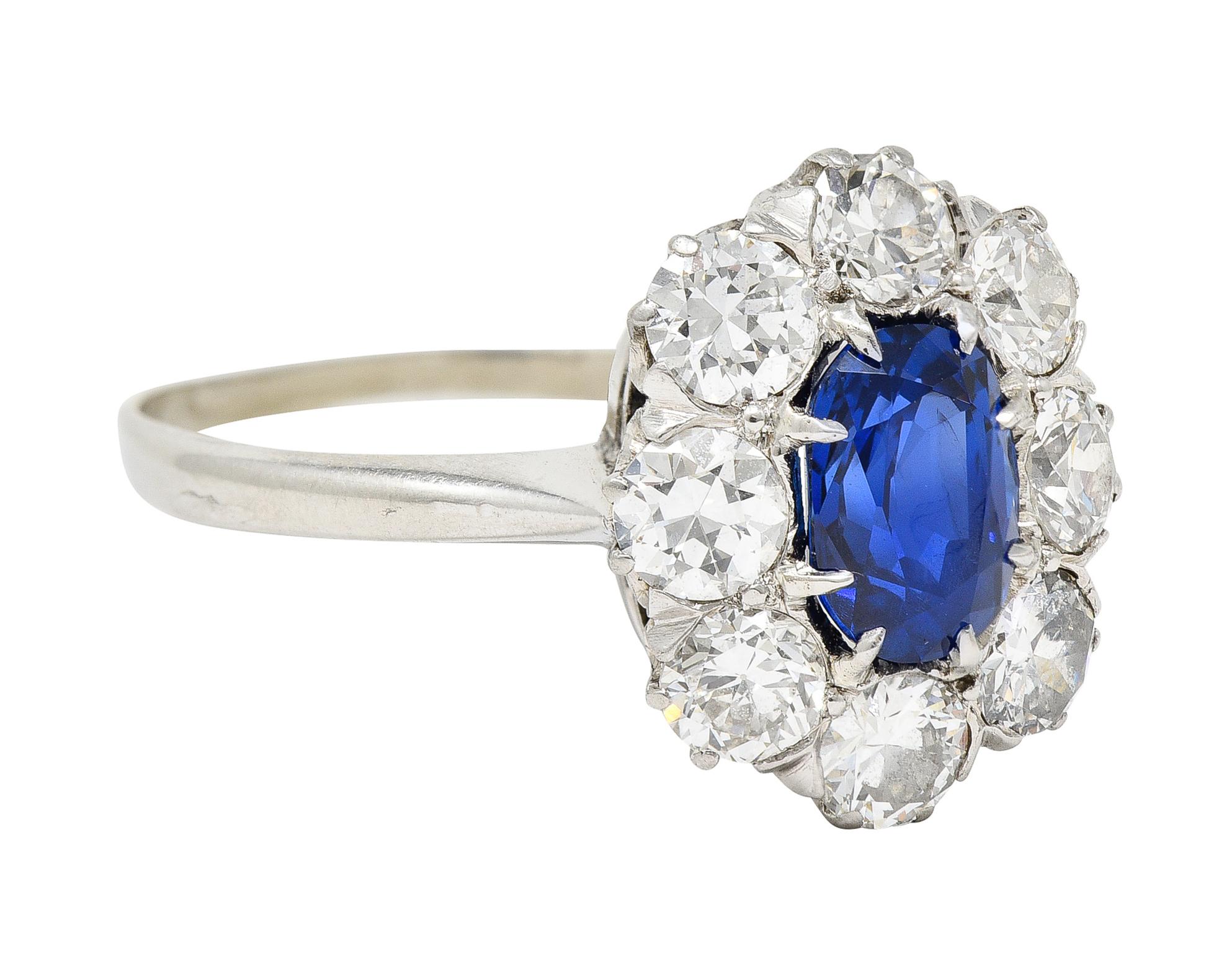 Centering an oval cut sapphire weighing 1.20 carats - transparent deep blue. Natural Burmese in origin with no indications of heat treatment. Set with talon prongs with a halo surround of old European cut diamonds. Weighing approximately 1.28 carats