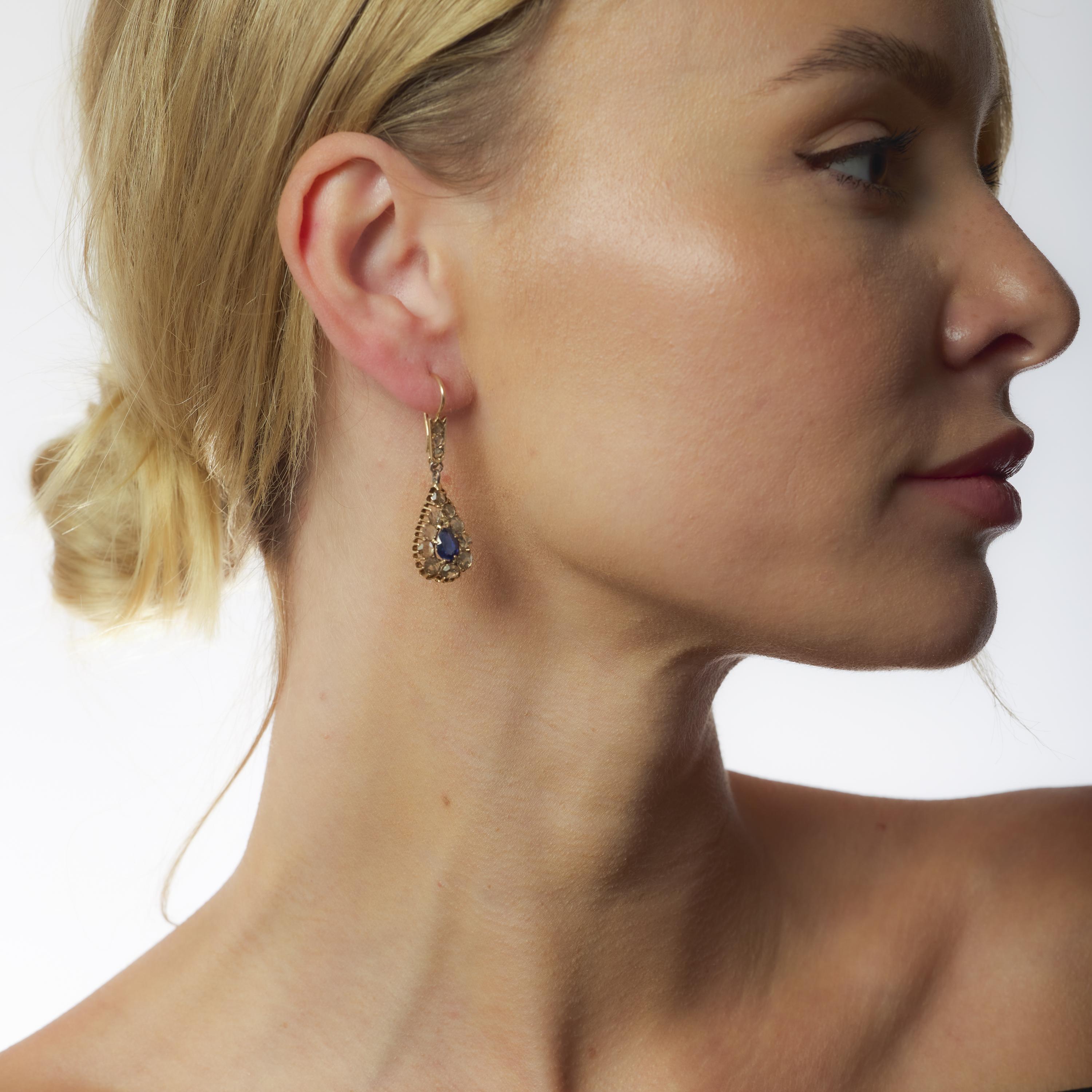 These Edwardian 14k rose gold earrings showcase vivid pear sapphires framed by antique rose cut diamonds in a graceful, elongated silhouette.