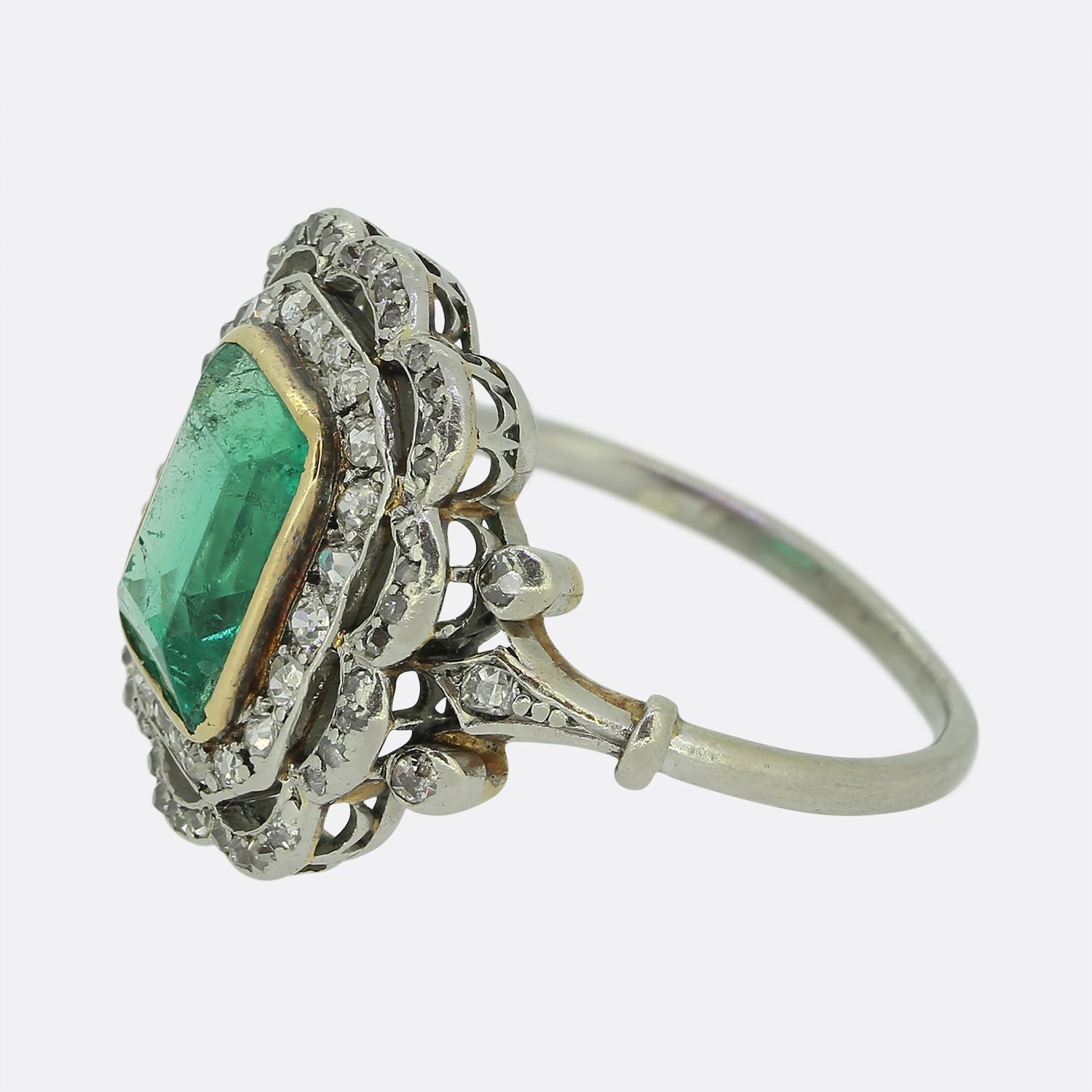 Here we have a delightful emerald and diamond cluster ring taken from the early stages of the 20th century. An impressive 2.60 carat emerald cut emerald of Colombian origin possessing a lively electric green colour tone has been set at the centre of