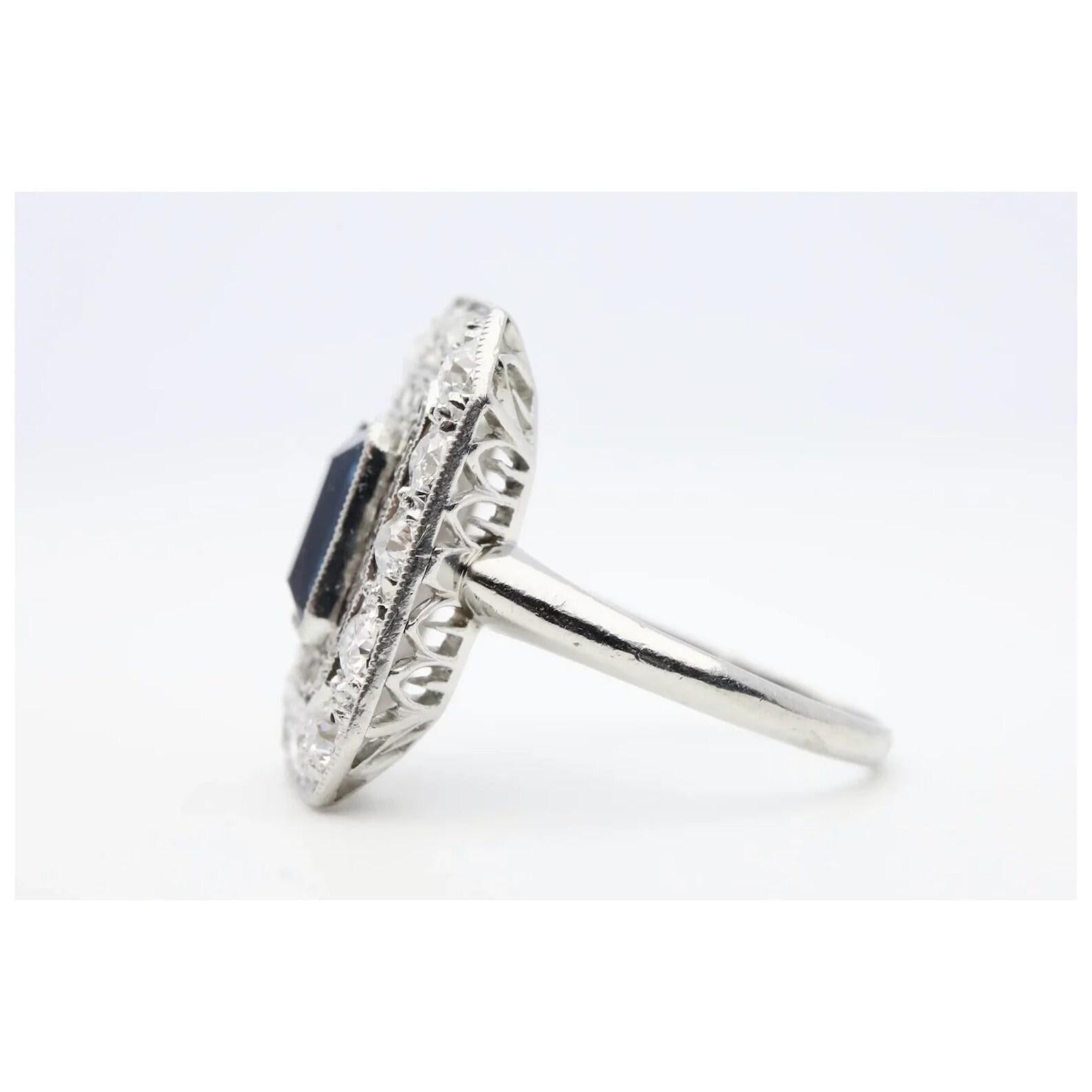 A beautiful handmade Edwardian period sapphire, and diamond filigree ring in platinum. Centered by a 1.25 carat natural No Heat rectangular sapphire of beautiful rich velvety blue color in a miligrained platinum bezel setting. Framing the sapphire