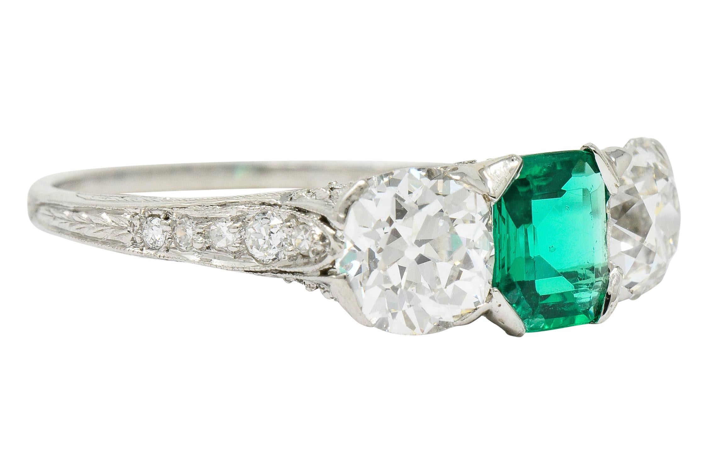 Centering an emerald cut emerald weighing approximately 0.62 carat, very transparent with a bright viridian color

Flanked by two old mine cut diamonds weighing in total approximately 1.74 carats, G/H color with VS clarity

With ornate gallery and