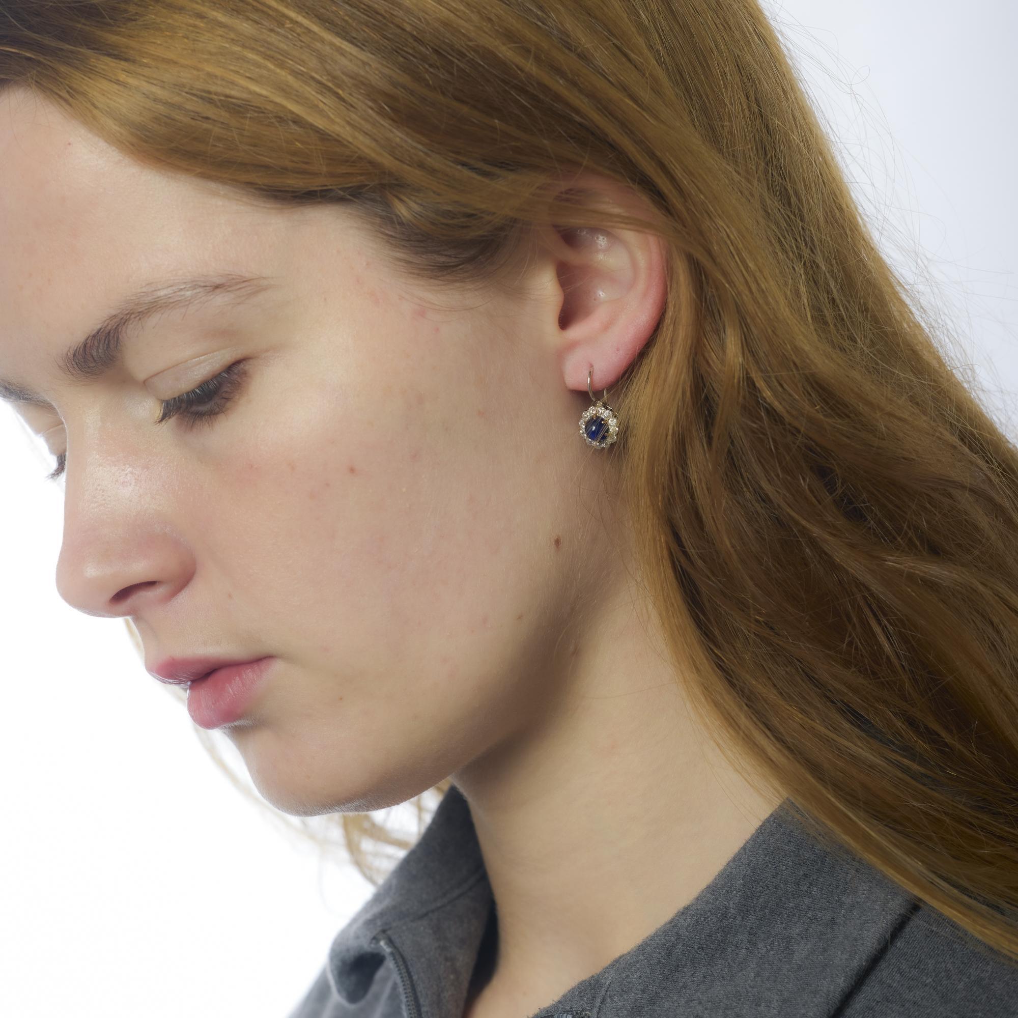 These Edwardian platinum earrings feature rich cabochon sapphires surrounded by old European cut diamonds, radiating delicate elegance and refined vintage allure.