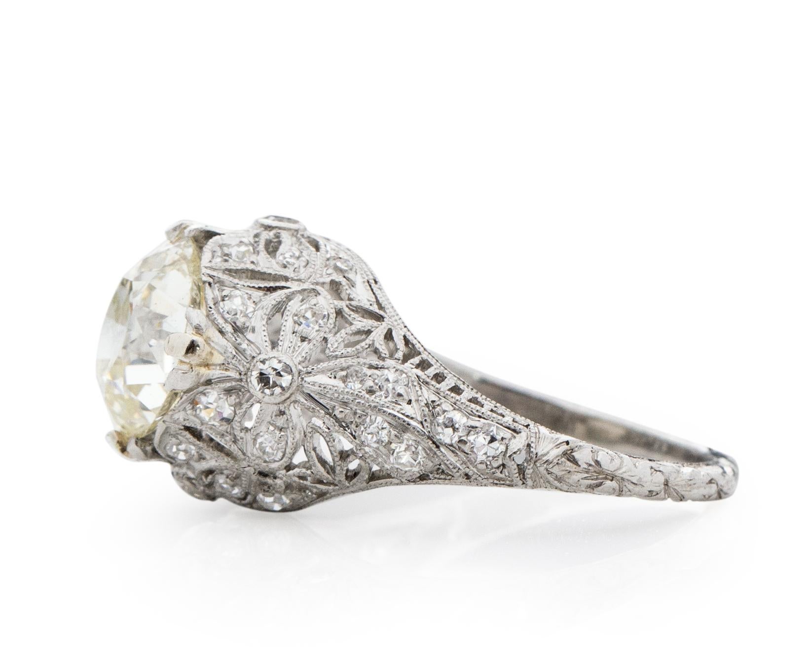 This piece is a show stopper, a beautiful old mine cut diamond in the center. Surrounded by intricate filigree engravings winding all the way around the ring, along with beautiful accent diamonds along the sides of the center diamond and about half