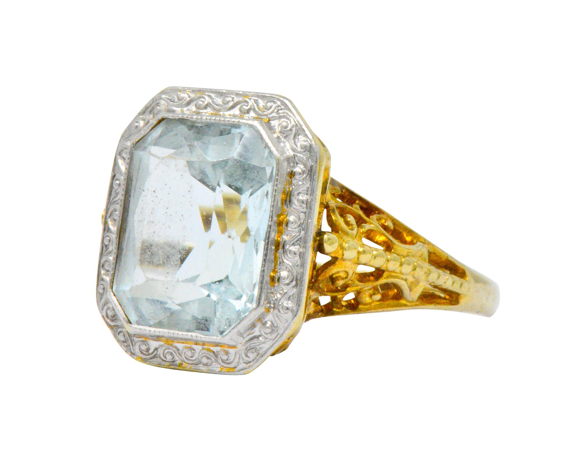 Centering a cut-corner scissor cut aquamarine weighing approximately 3.00 carats, very slightly light greenish blue

With a scrolling platinum surround

Highly detailed pierced stylized gold gallery

Tested as 14 karat gold

Circa 1910

Ring Size: 6