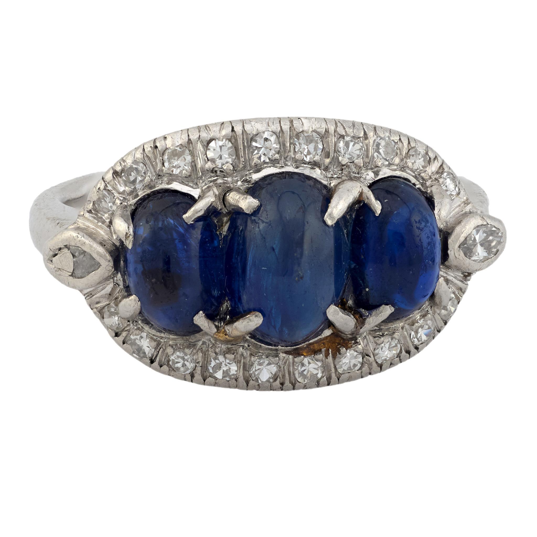 This Edwardian platinum ring showcases three luminous cabochon sapphires framed by sparkling single and marquise cut diamonds for a refined antique silhouette.