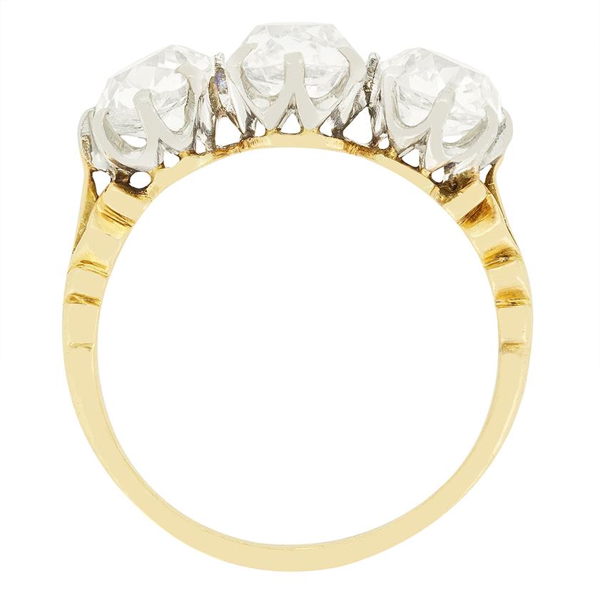 Un trio de diamants anciens de taille coussin est magnifiquement mis en valeur dans cette bague de style édouardien. La pierre centrale est la plus grosse (1,35 carat), tandis que les deux pierres latérales sont de 1,00 carat chacune. Les trois
