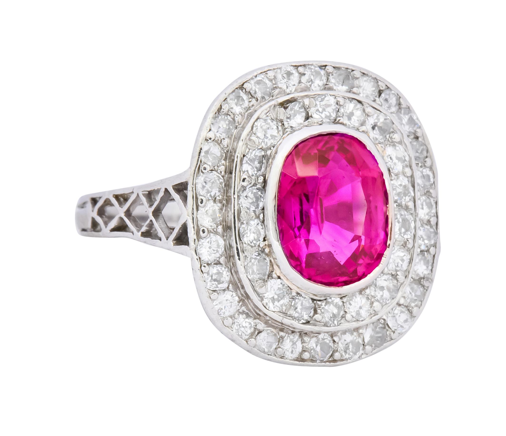 Centering a bezel set oval mixed cut Burmese ruby weighing 2.37 carats, transparent and raspberry red in color

Surrounded by a double halo of round brilliant cut diamonds weighing approximately 1.00 carat total, G to I color and SI clarity

With a