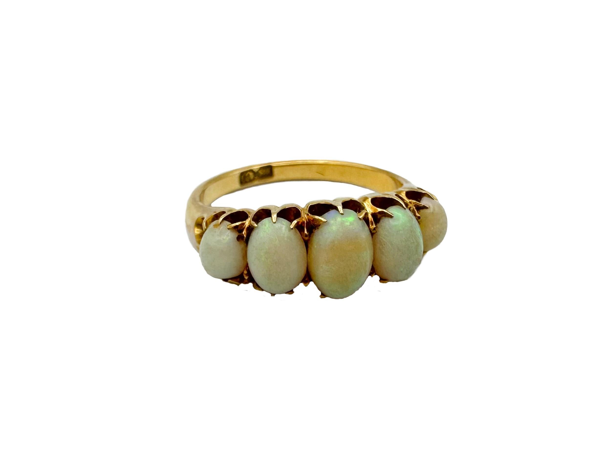 Antique Edwardian 5 stone white opal ring (circa 1910s), crafted in 18 karat yellow gold. The opals are set in a classic graduated 5 stone setting. The egg-shaped natural opals have a milky white bodycolor with a color play of fine bands and dots of