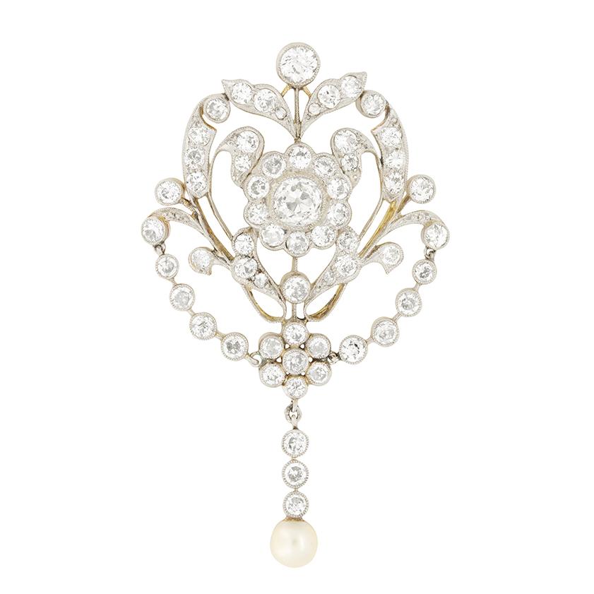 This intricate piece of Edwardian craftsmanship features a collection of old cut diamonds and finished with a single pearl. The main diamond sitting central to the piece is 0.75 carat and rub over set. It is surrounded by a halo of diamonds with the
