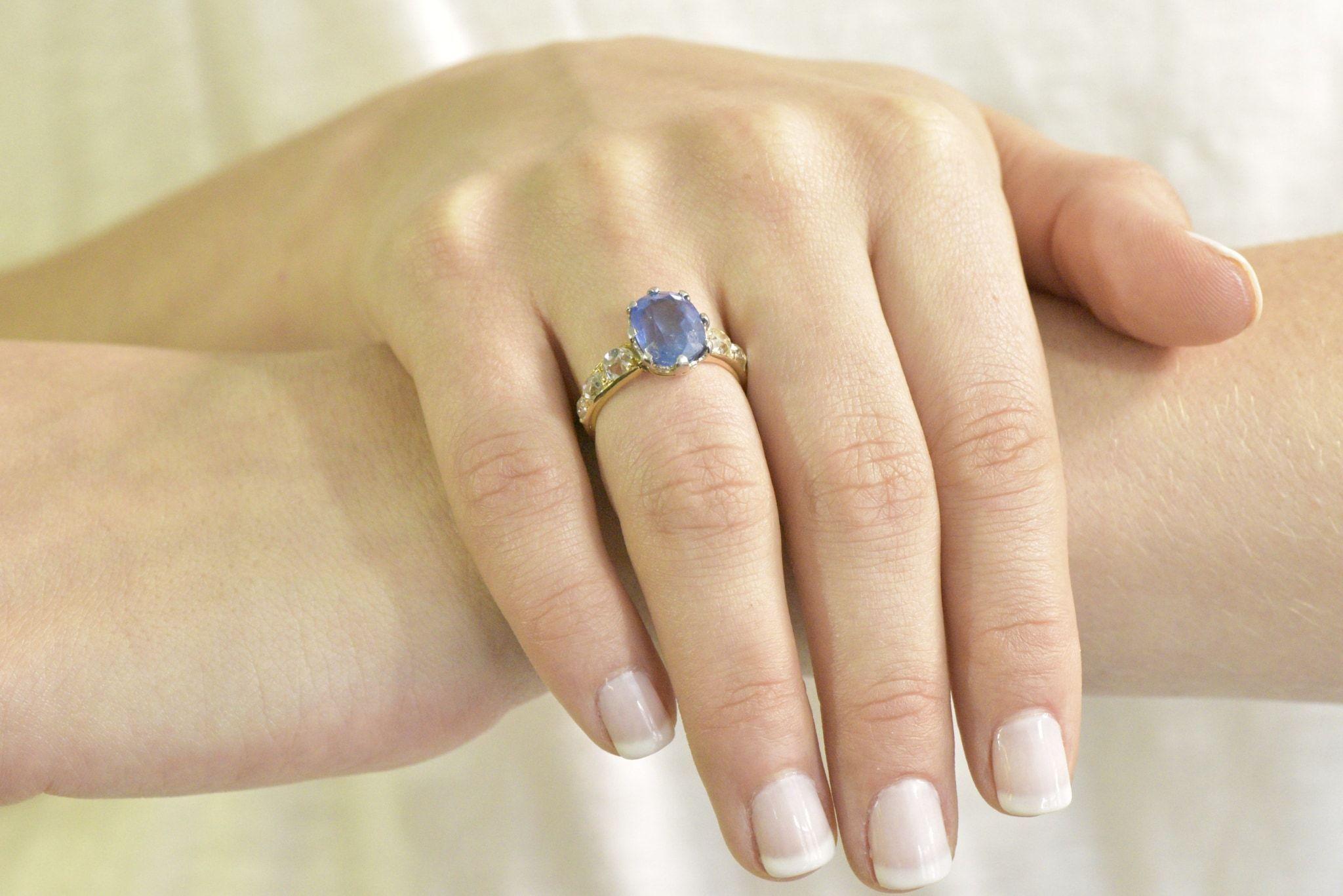 Centering a natural 6.96 carat unheated cornflower blue Ceylon sapphire with very slight natural inclusions 

Prong set in platinum with heart motif filigree surround

Flanked by old mine cut diamonds weighing approximately 1.70 carats;  I to J