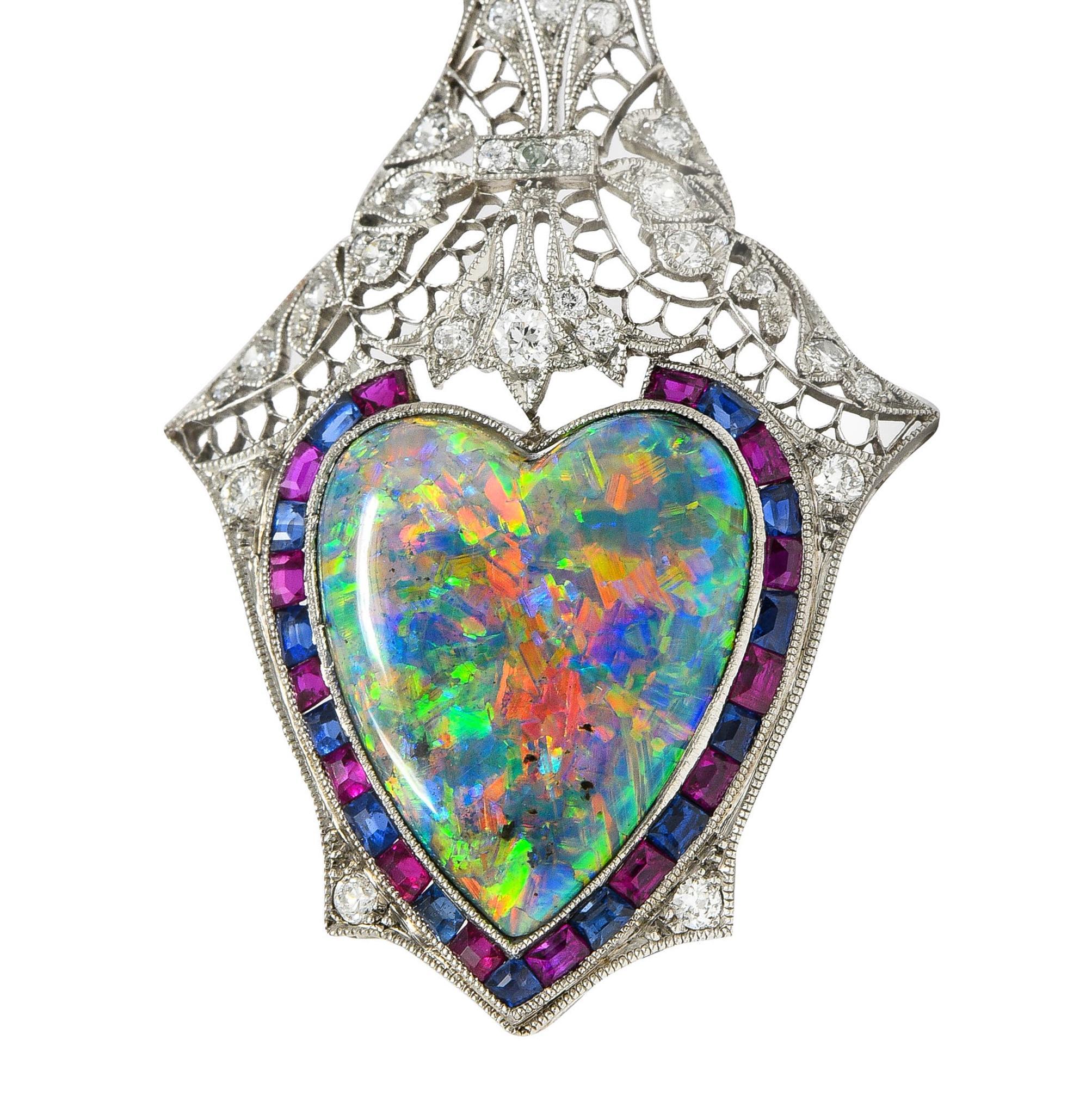 Designed as an ornately pierced plaque-shaped pendant and bale with filigree and flowing foliate motifs
Featuring a heart-shaped opal cabochon weighing approximately 6.42 carats - bezel set
Black in body color with spectral play-of-color and subtle