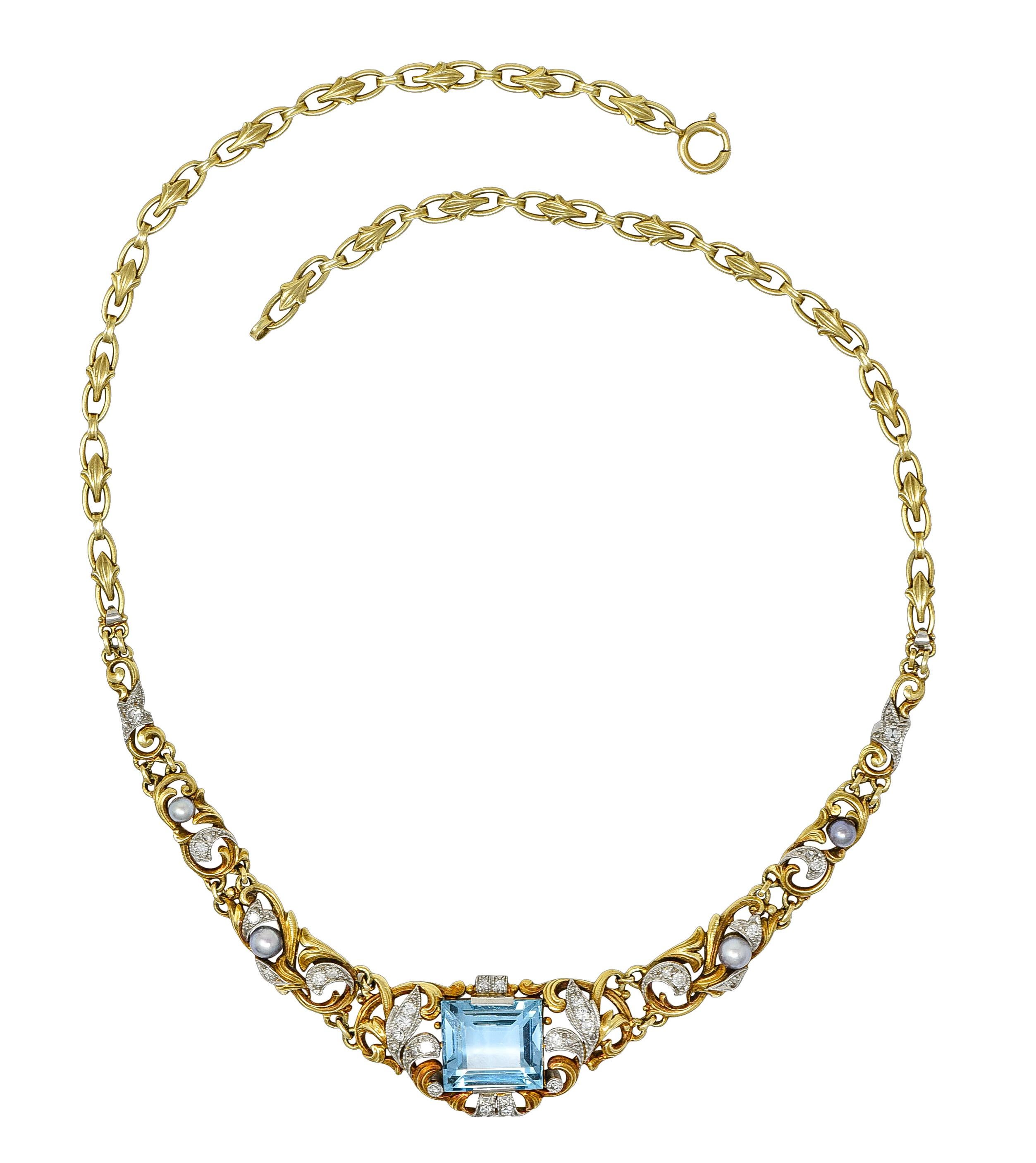 Designed as a stylized fleur-de-lis motif cable chain featuring a scrolling central station. Centering a step-cut aquamarine weighing approximately 9.06 carats total. Transparent blue in color with light saturation - tab set in ornate surround.