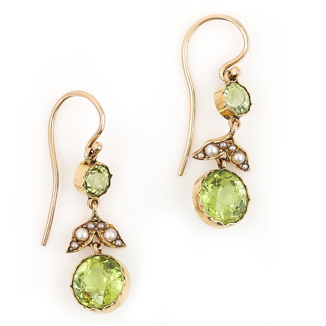 A delightfully pretty pair of Edwardian drop earrings set with a main round mixed cut peridot and seed pearls. Dating from the early 20th century these antique earrings are so beautiful in their design and craftsmanship. The round peridot drops of