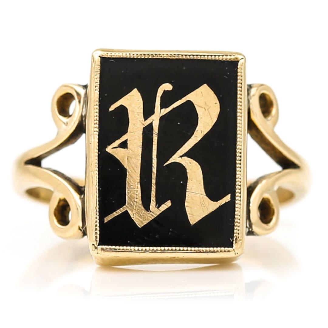 A statement Edwardian 9ct gold onyx ring dating from the early 20th century with an ornate 'R' initial in blackletter typeface to the centre. Set in a rectangular head the large (possibly gentlemen’s) ring has a beautifully hand carved gold letter