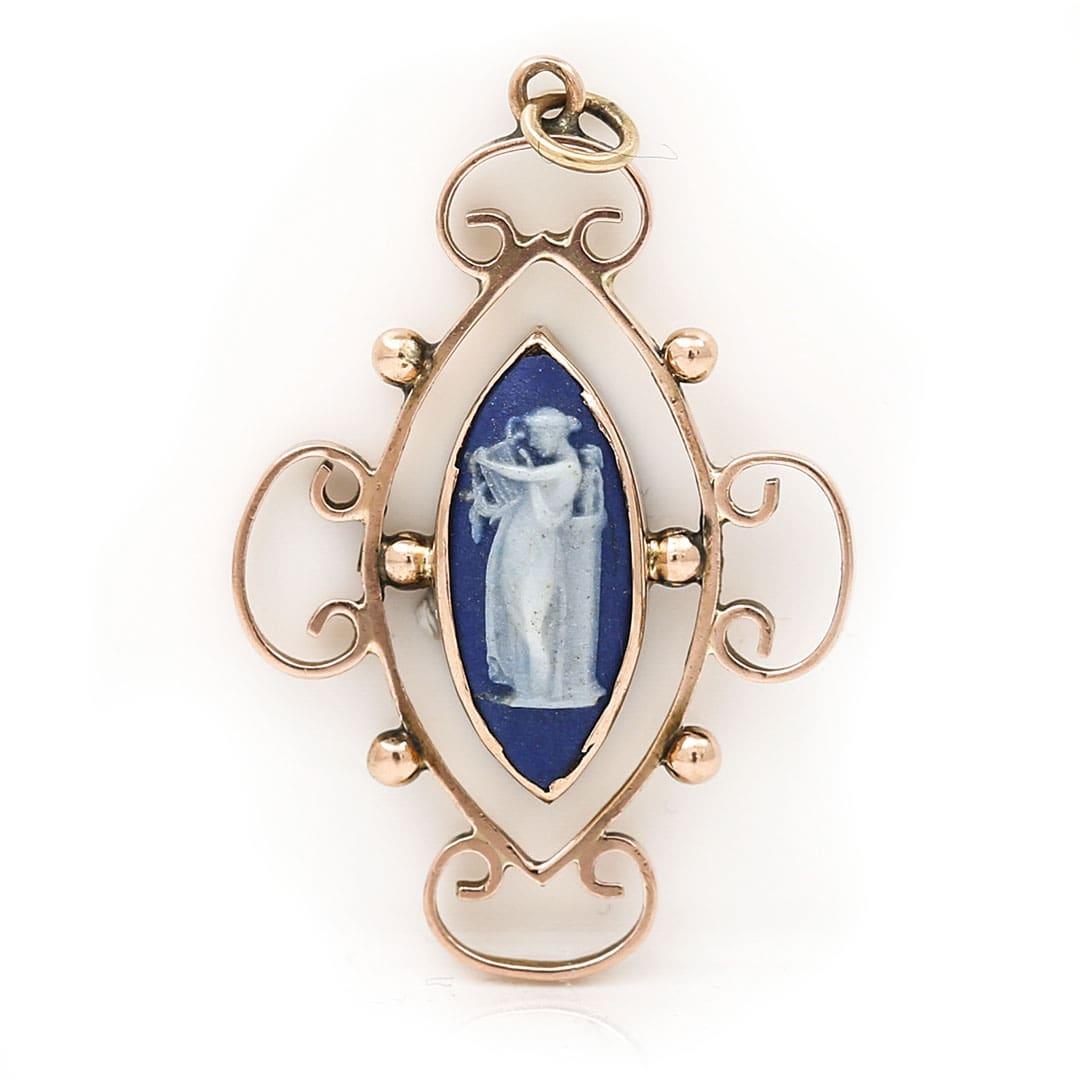 A very pretty and ornate 9ct rose gold Edwardian antique pendant with a central set blue Wedgwood Jasperware cameo scene depicting Calliope playing the lyre. The tapered oval royal blue cameo has the distinct ‘Wedgewood’ markings to the reverse