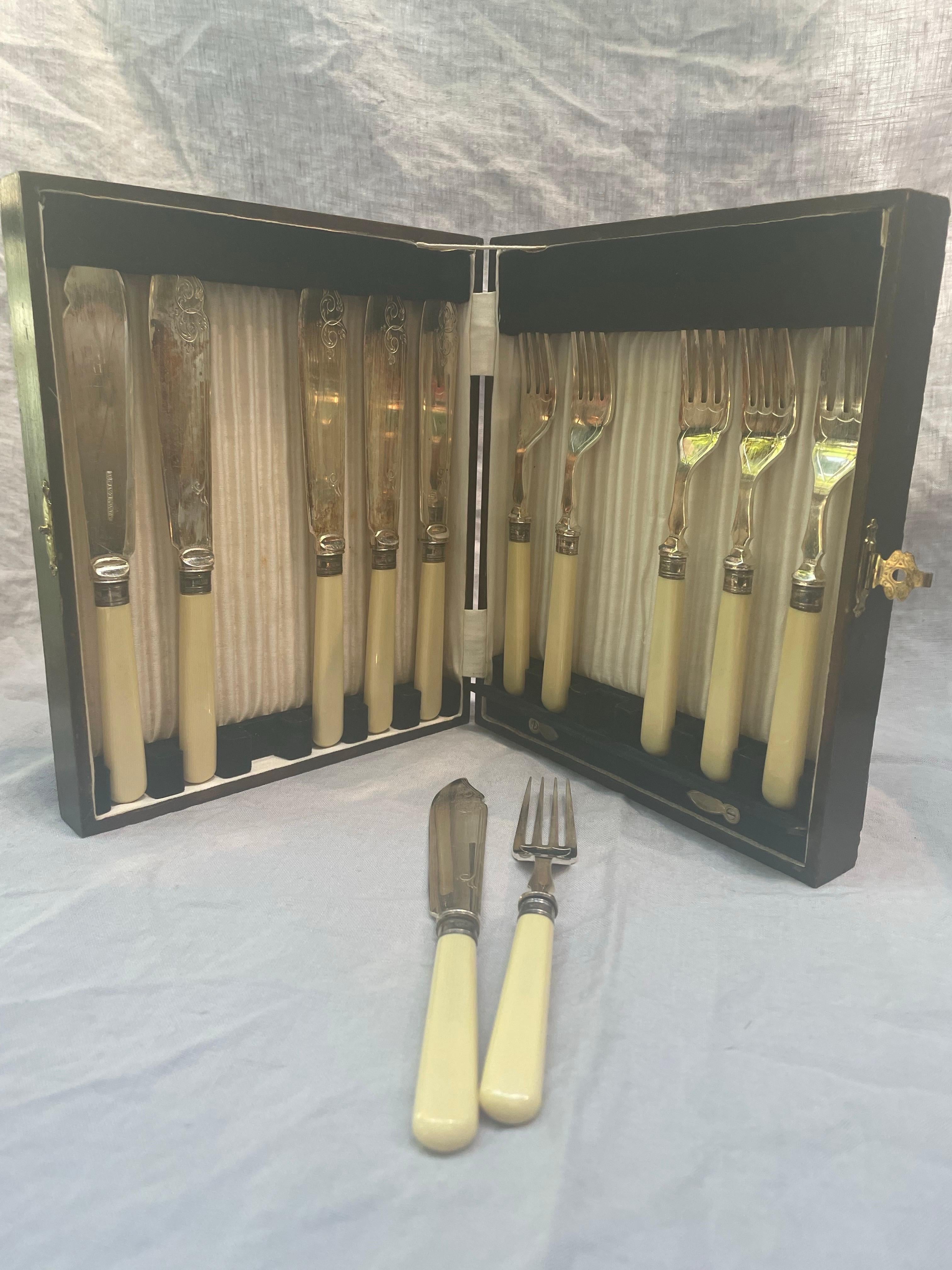 A fine early 20th-century English twelve-piece fish set, marked S.M. & Co. EPNS A1, presented in its original fitted wooden case with brass clasp. Each piece features engraved silver-plated blades and tines, complemented by elegantly tapered cream