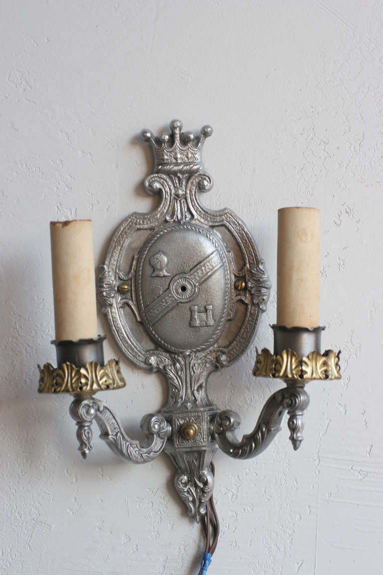 Edwardian aluminum wall sconce featuring a center crest with crown, armor head and castle.