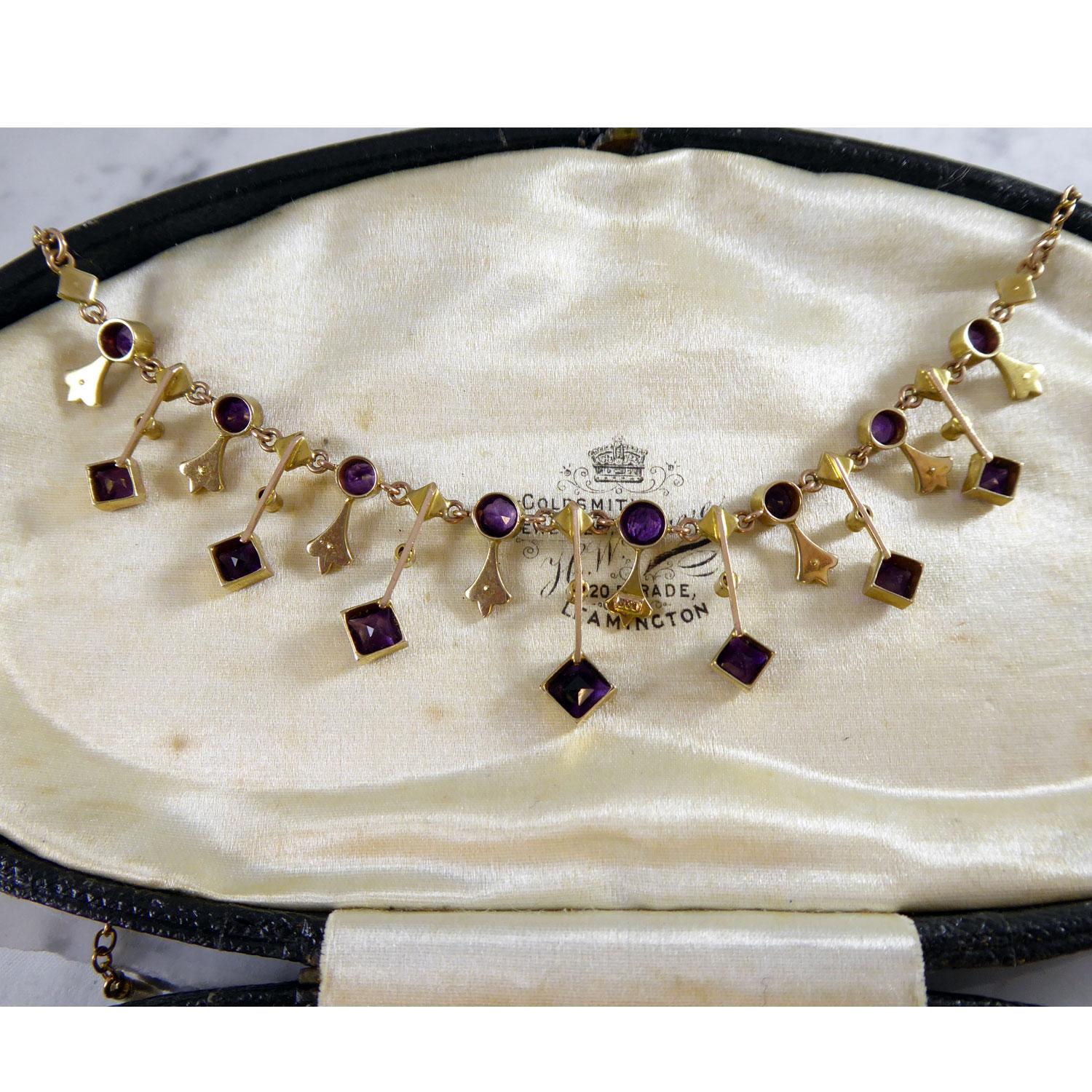 A charming amethyst and pearl necklace from the Edwardian era set with eight round mixed cut amethysts and nine half seed pearls, which form the first row of the necklace and which attach at either side to a gold trace chain.  From this section