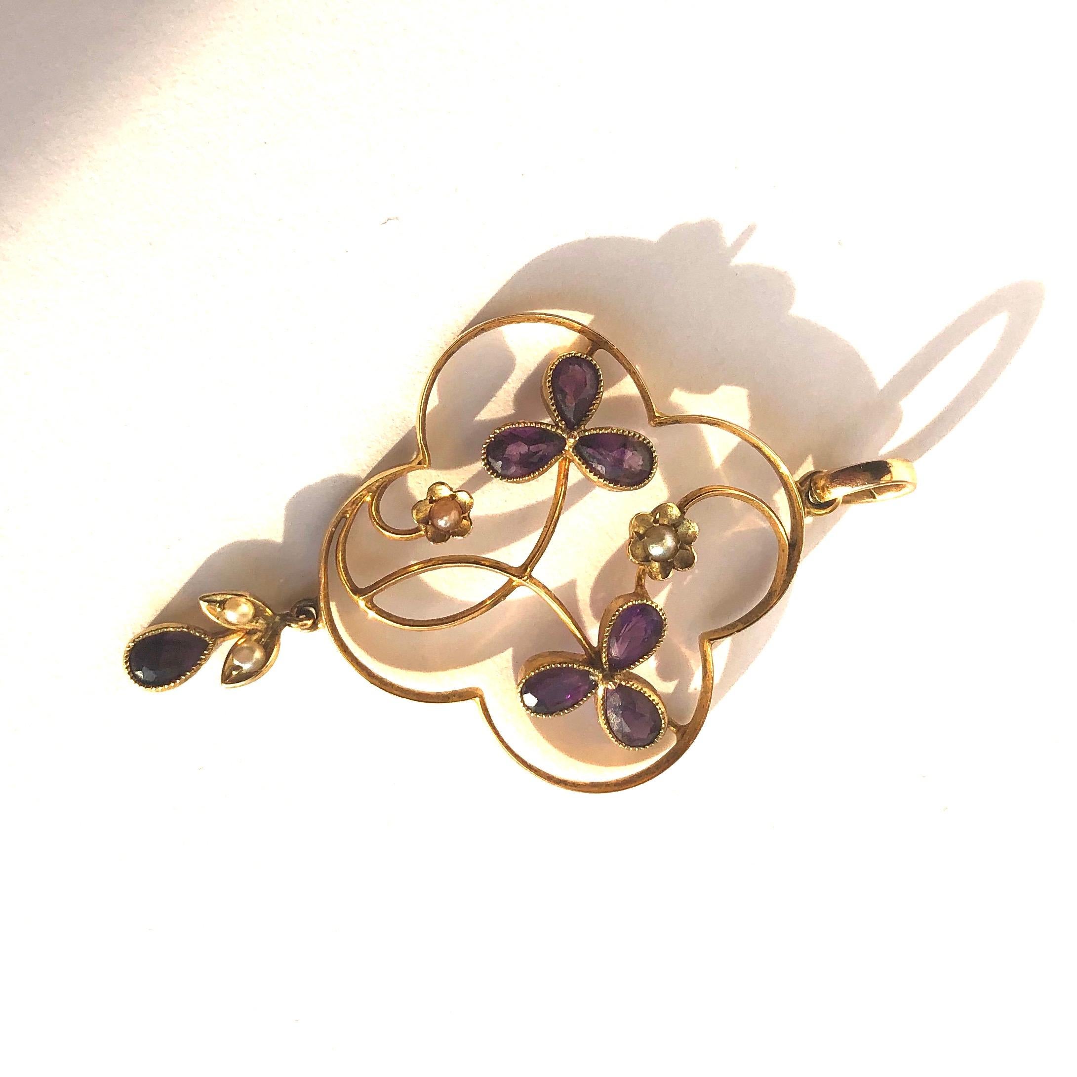 The style of this pendant is so delicate with the fine metal work and is beautifully decorated with pearls and amethyst. The central oval amethyst measures 30pts. The seed pearls surround the central stone on gold leaves and the loop even holds a