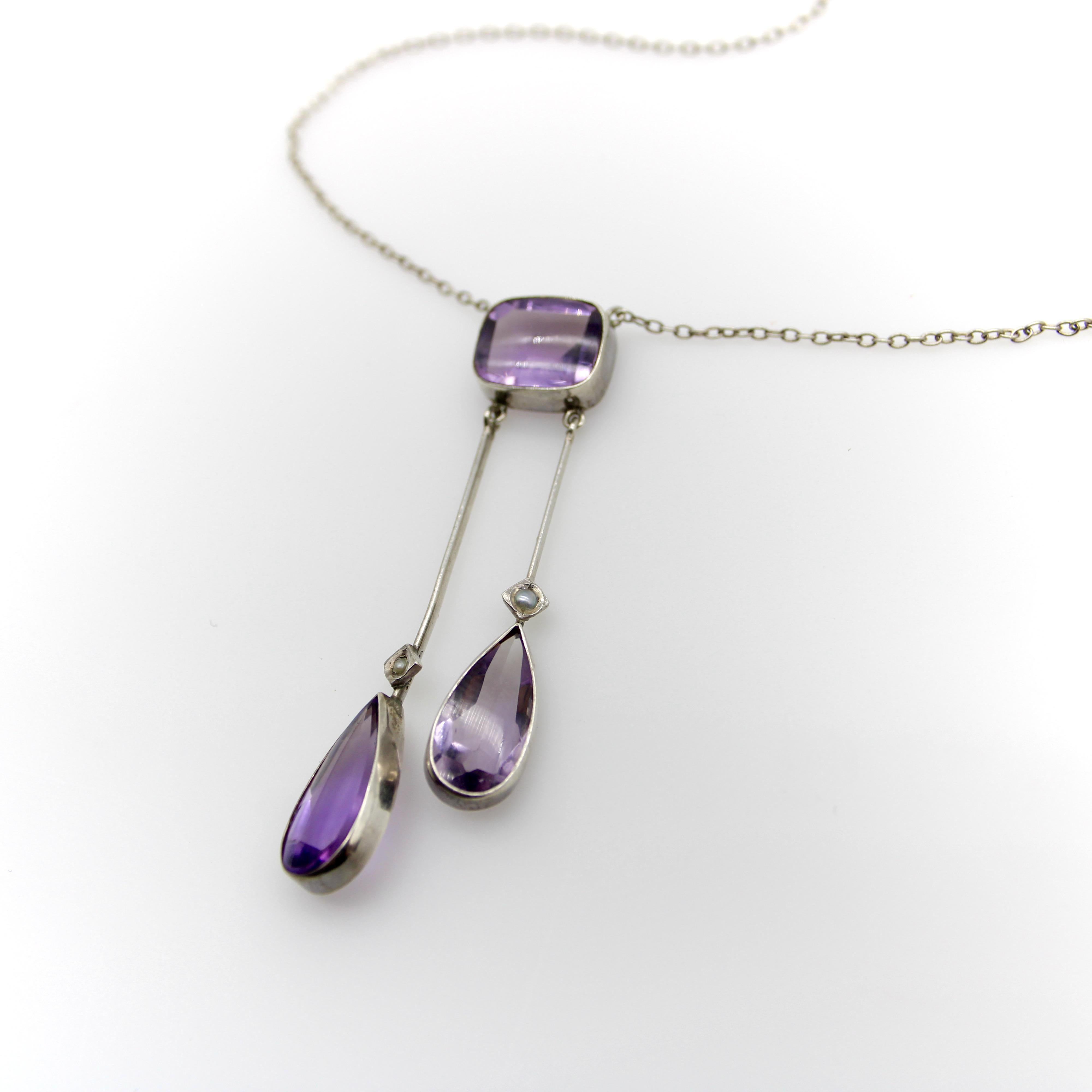 This sterling silver Edwardian negligee necklace features amethyst cabochon tear drops that dangle from a larger amethyst centerpiece. The amethysts are modified emerald and pear-shaped cuts—smooth cabochon tops with faceted backs. The effect is