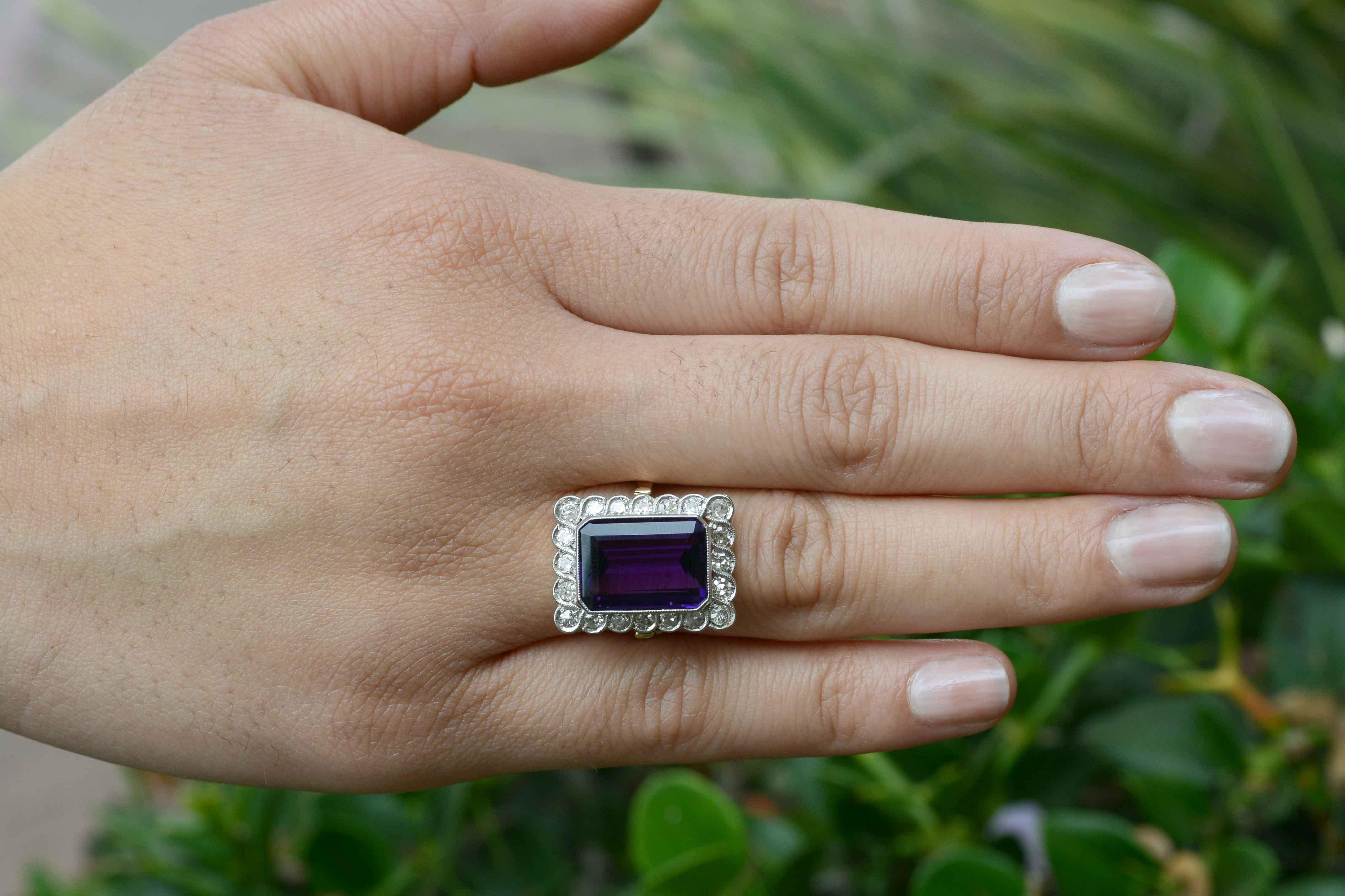A wonderful example of antique Edwardian jewelry, this circa 1913 stunner is centered by a deeply saturated, velvety and rich royal purple gemstone. At a sizable 6.50 carats of emerald cut beauty and held within a platinum milgrained bezel