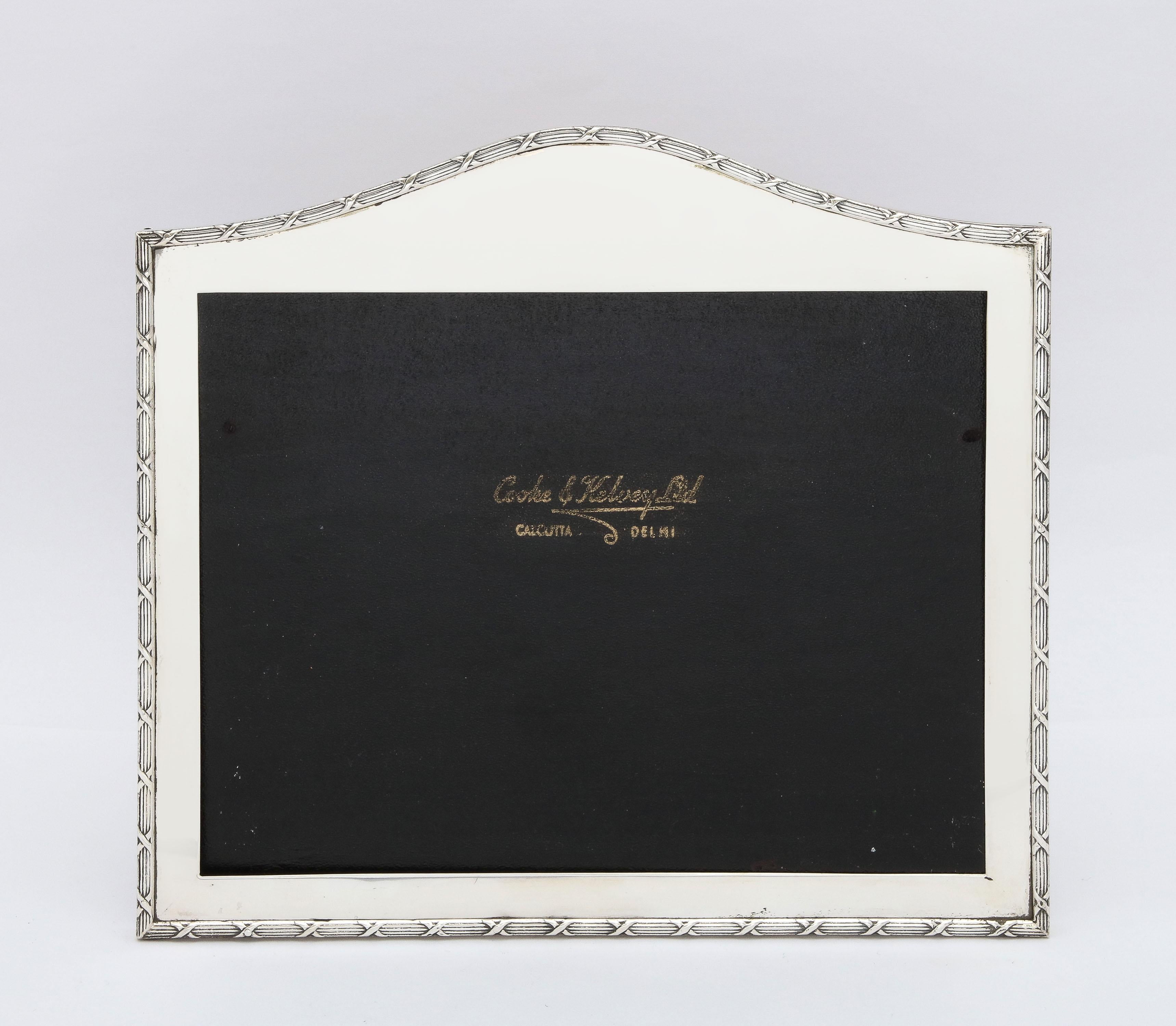 Large, Edwardian Period, Anglo-Indian, sterling silver, Hump-topped picture frame with wood back, Calcutta/Delhi, India, 1910, Cooke and Kelvy - makers. Ribbon and reed borders. Measures 8 1/2 inches high (at highest point) x 9 1/4 inches wide (at