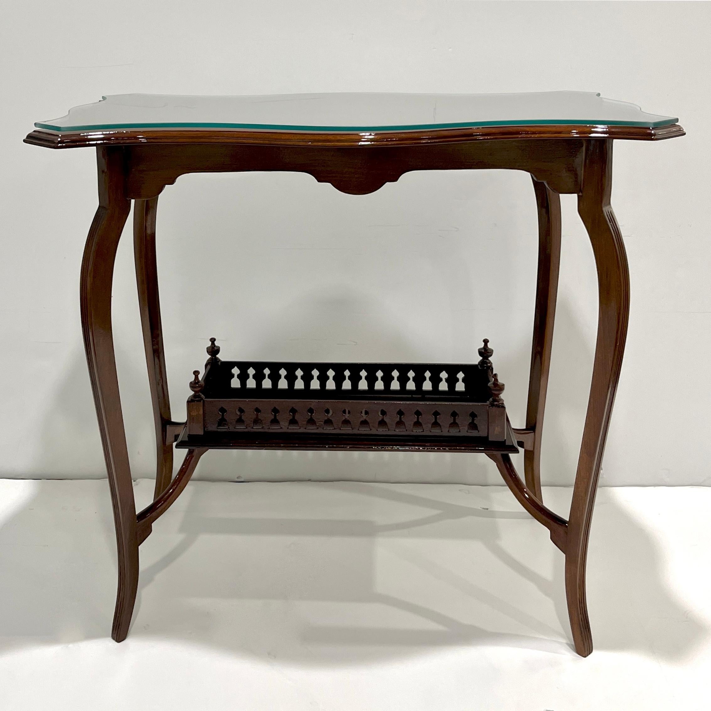 Cette élégante table d'appoint en bois d'acajou anglais, datant d'environ 1910, est un exemple raffiné de l'artisanat de la fin de la période édouardienne. La table est dotée d'un plateau de forme magnifique équipé d'une épaisse surface en verre