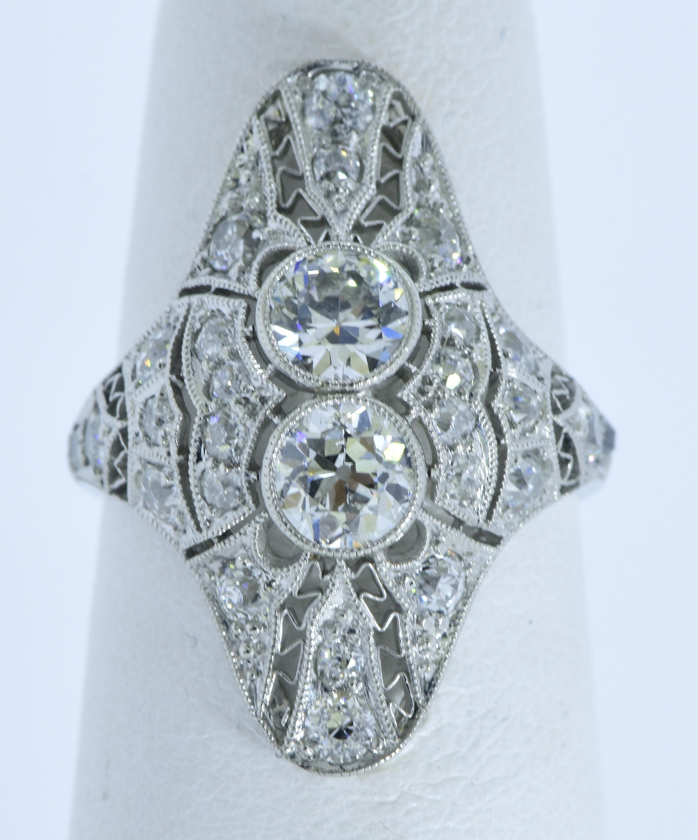Platinum and diamond antique ring from the Edwardian time period.  There are 27  early European cut diamonds.  The two larger center diamonds are bezel set in milgrained bezels, the surrounding smaller diamonds (also early European cut diamonds) are