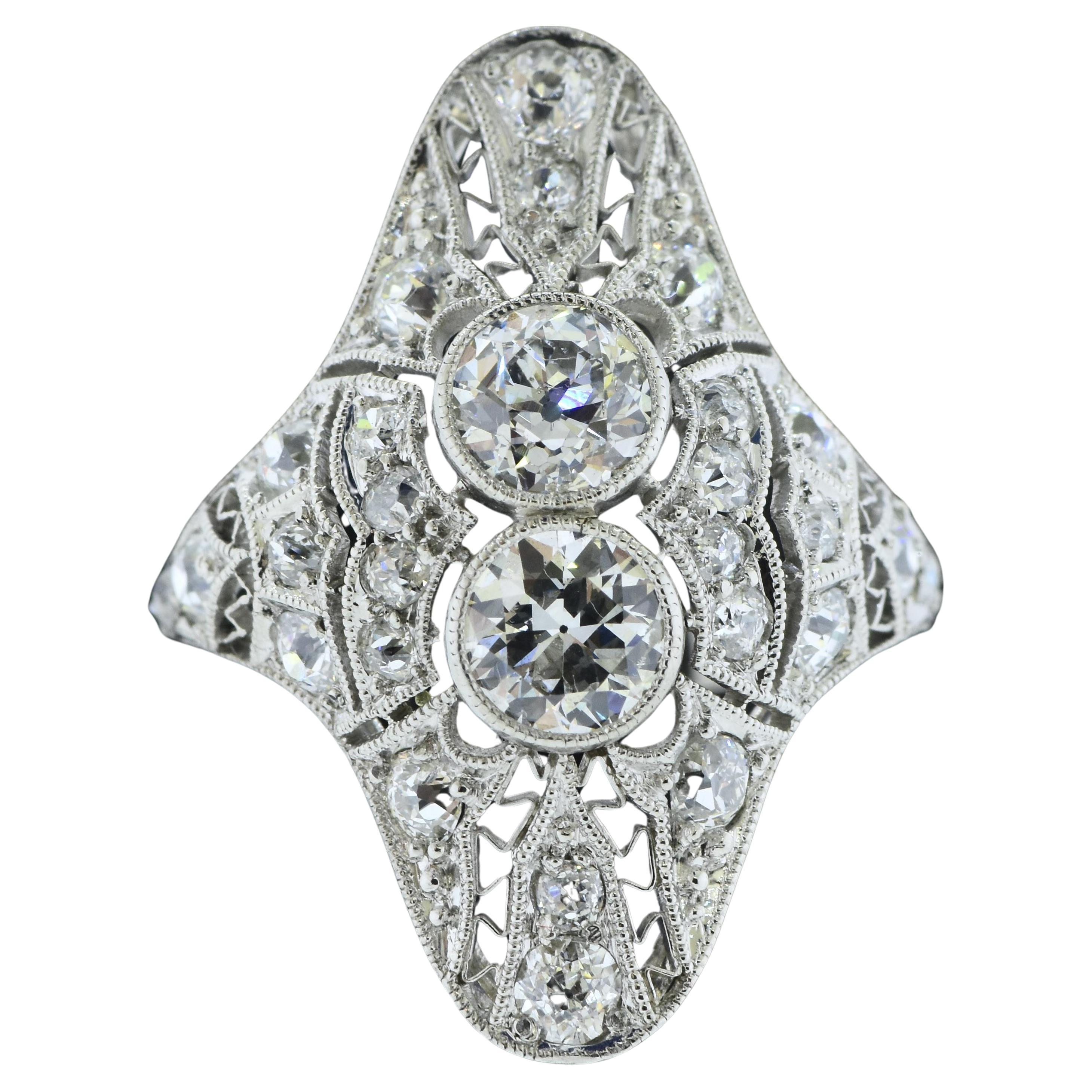 Platinum and diamond antique ring from the Edwardian time period.  There are 27  early European cut diamonds.  The two larger center diamonds are bezel set in milgrained bezels, the surrounding smaller diamonds (also early European cut diamonds) are