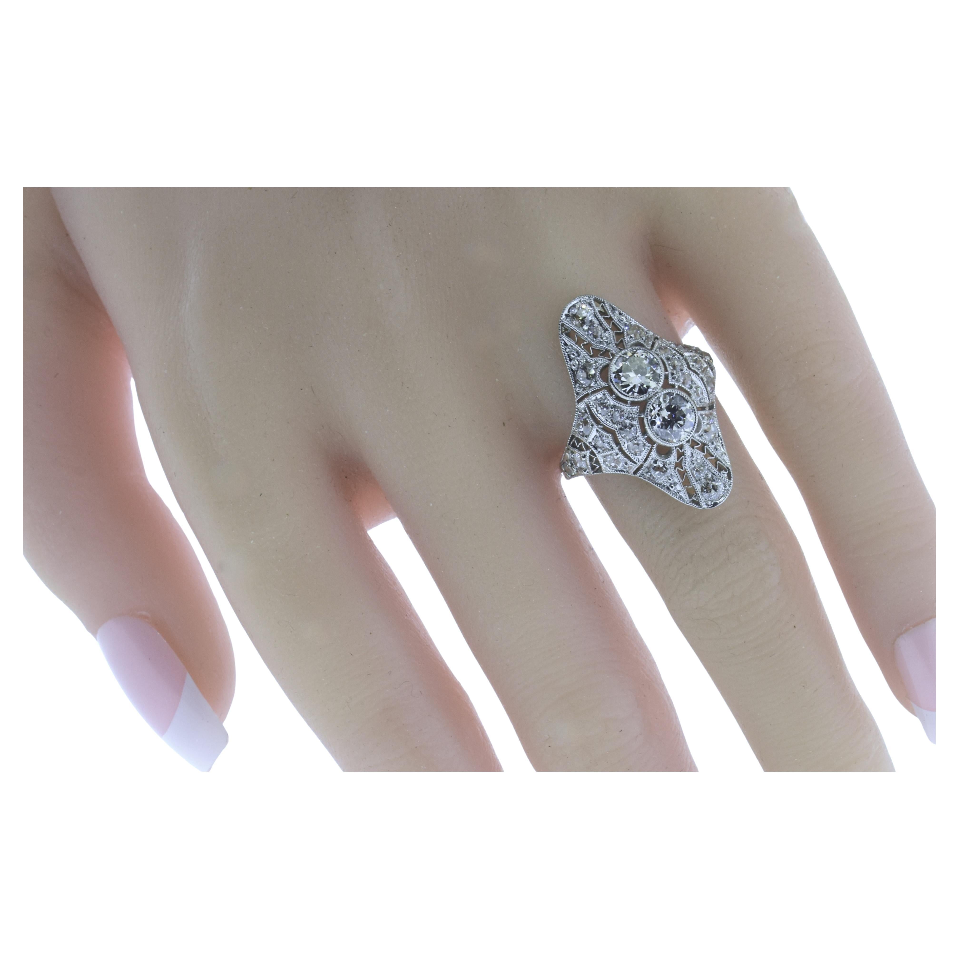 Anello antico in platino e diamanti del periodo edoardiano.  Ci sono 27  diamanti tagliati all'inizio dell'Europa.  I due diamanti centrali più grandi sono incastonati in castoni a grana grossa, mentre i diamanti più piccoli circostanti (anch'essi