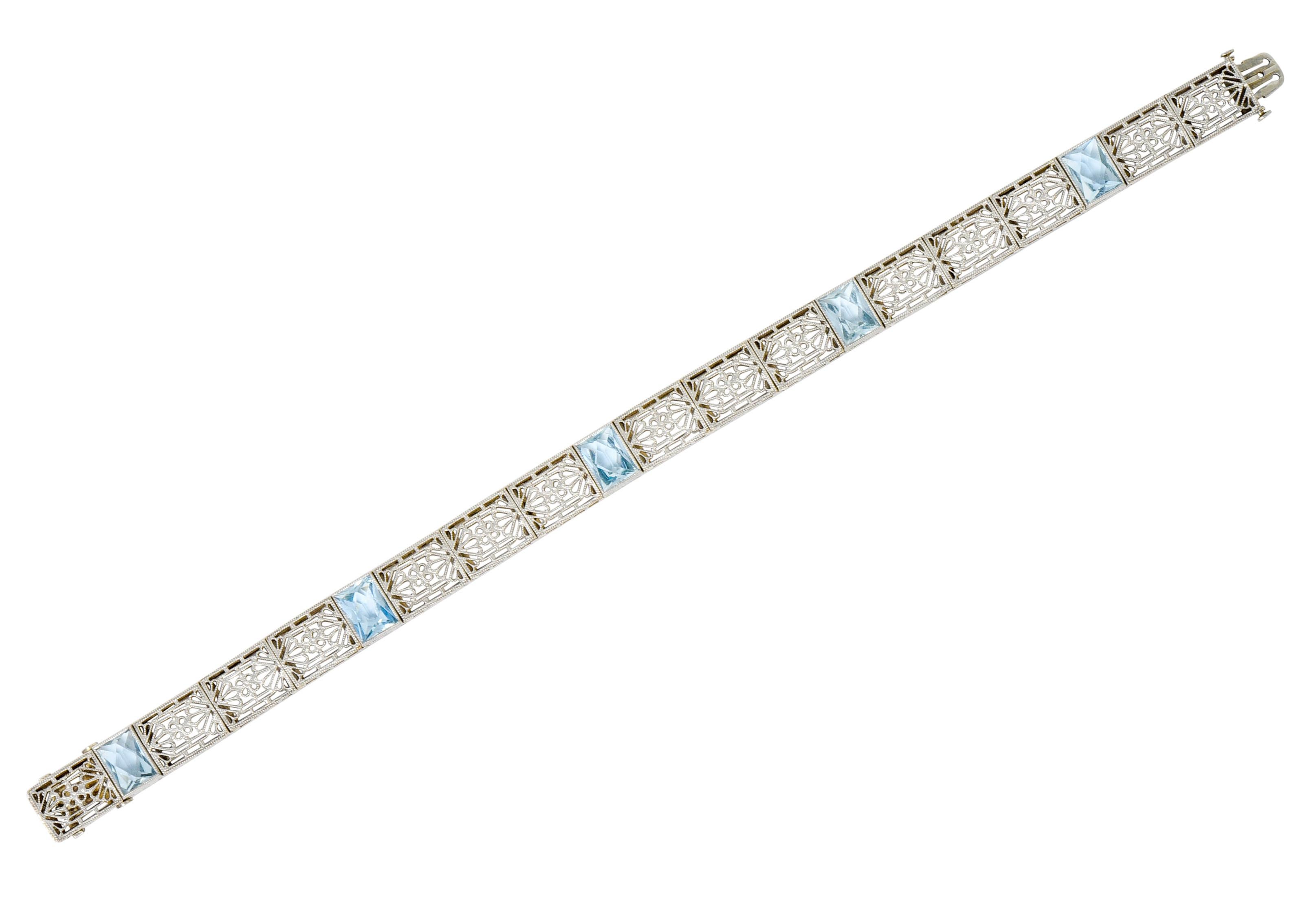 Streamlined bracelet comprised of intricately pierced milgrain links centering a flower motif within a geometric design accented by scalloped clam motif

Accented throughout by five bezel set rectangular French cut aquamarines, very well-matched and
