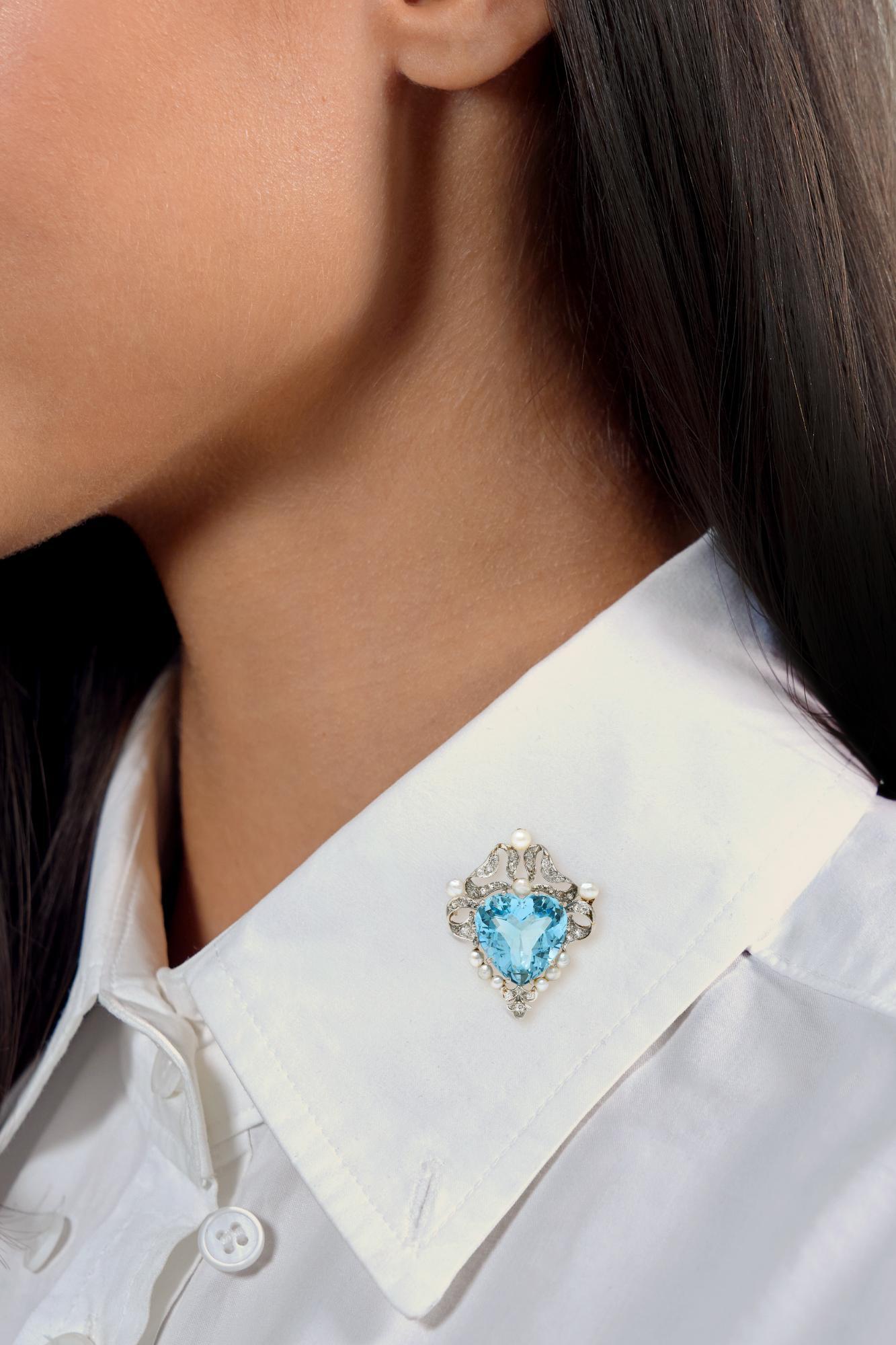 En el centro una aguamarina talla corazón de aproximadamente 12,72 quilates - de color azul claro transparente
Engastado con puntas en forma de garra con un decorativo motivo de lazo rizado alrededor
Acabado en platino y engastado con diamantes