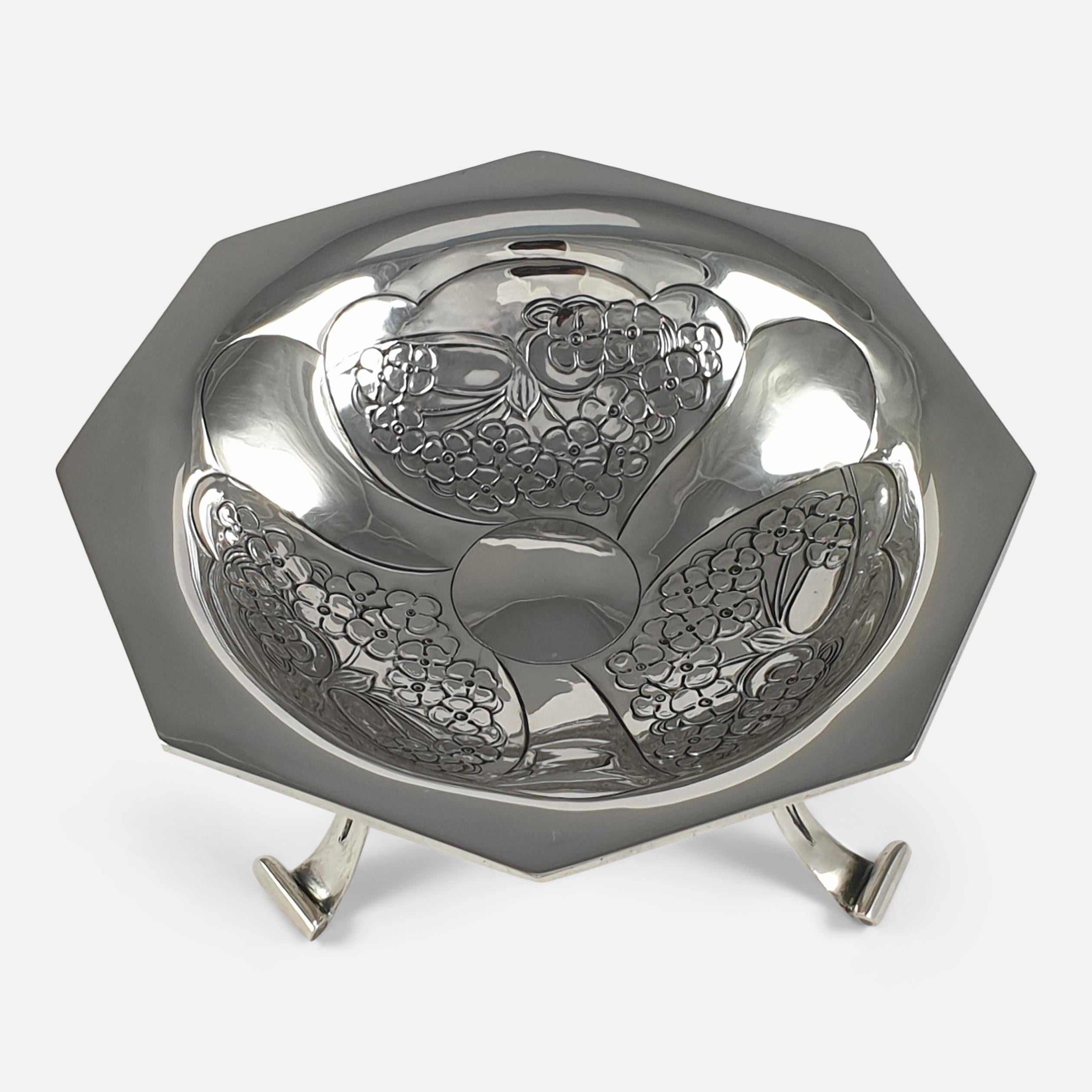 An Edwardian Art Nouveau sterling silver Tazza designed by Kate Harris for W.G. Connell. The Tazza is of octagonal form, with a chased foliate decoration to the bowl, and sits on three pierced scroll legs. It is hallmarked with the makers mark of