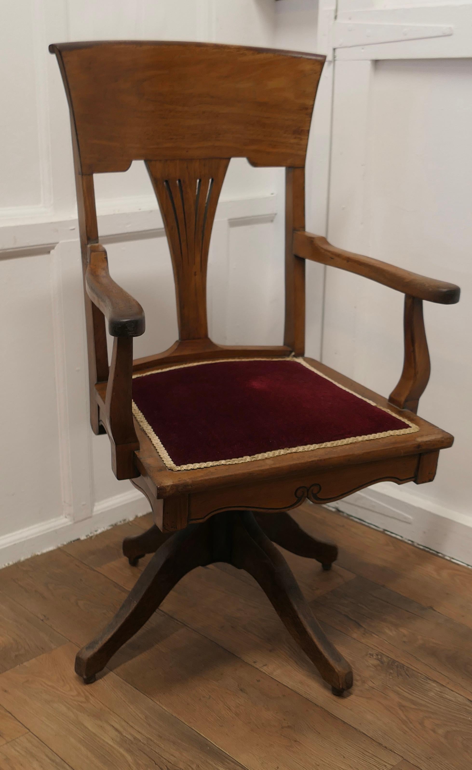Edwardian Arts and Crafts Walnut Desk or Office Chair  

The Chair has an attractive high curving back with a fan shape pierced splat and a wide curved top rail, the seat is upholstered with old Wine coloured velvet
This Stylish chair swivels easily