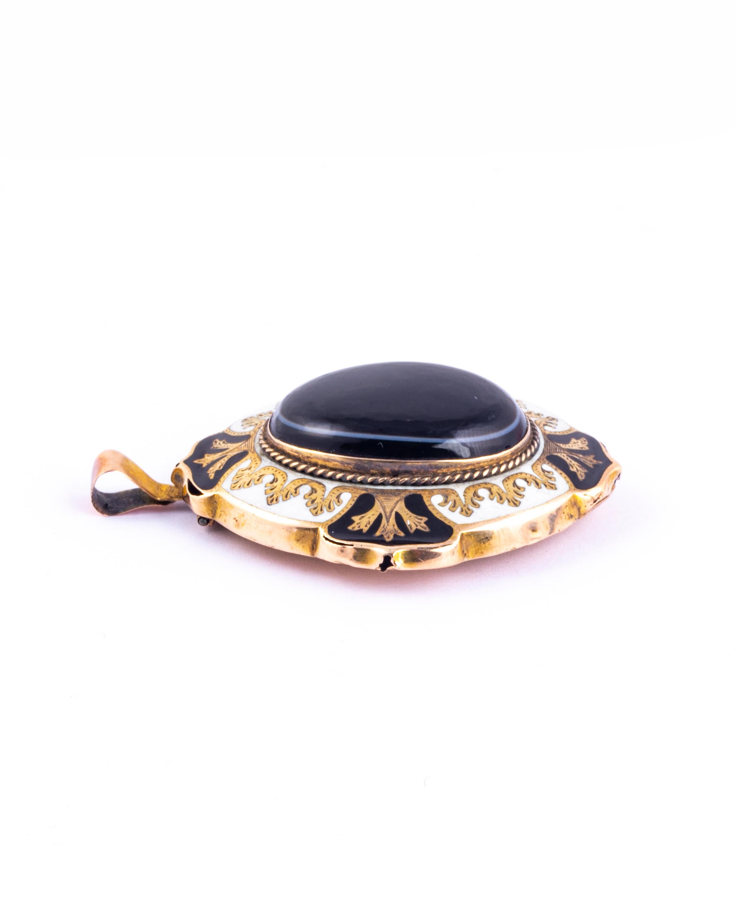 This wonderfully ornate locket holds a large glossy banded agate at the centre. Surrounding this stone is black and white enamel with intricate gold detail. Turn over this pendant and there is a locket back with the original glazed panel. modelled