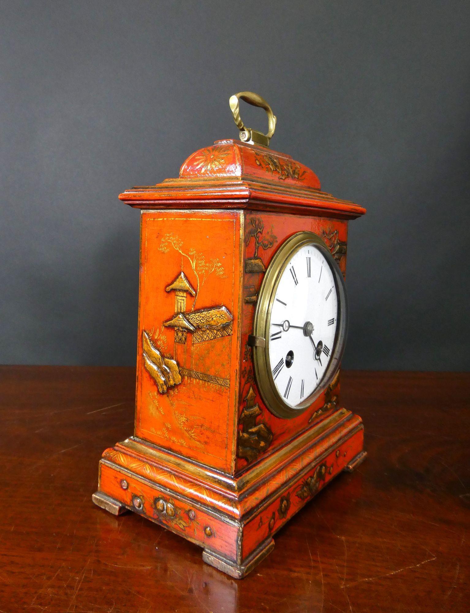 Edwardian Bell Top Chinoiserie Mantel Clock
Chinoiserie decorated mantel clock housed in a bell top case with raised scenes on a red ground, raised stepped plinth resting on four block feet surmounted by a brass carrying handle.
Brass bezel with