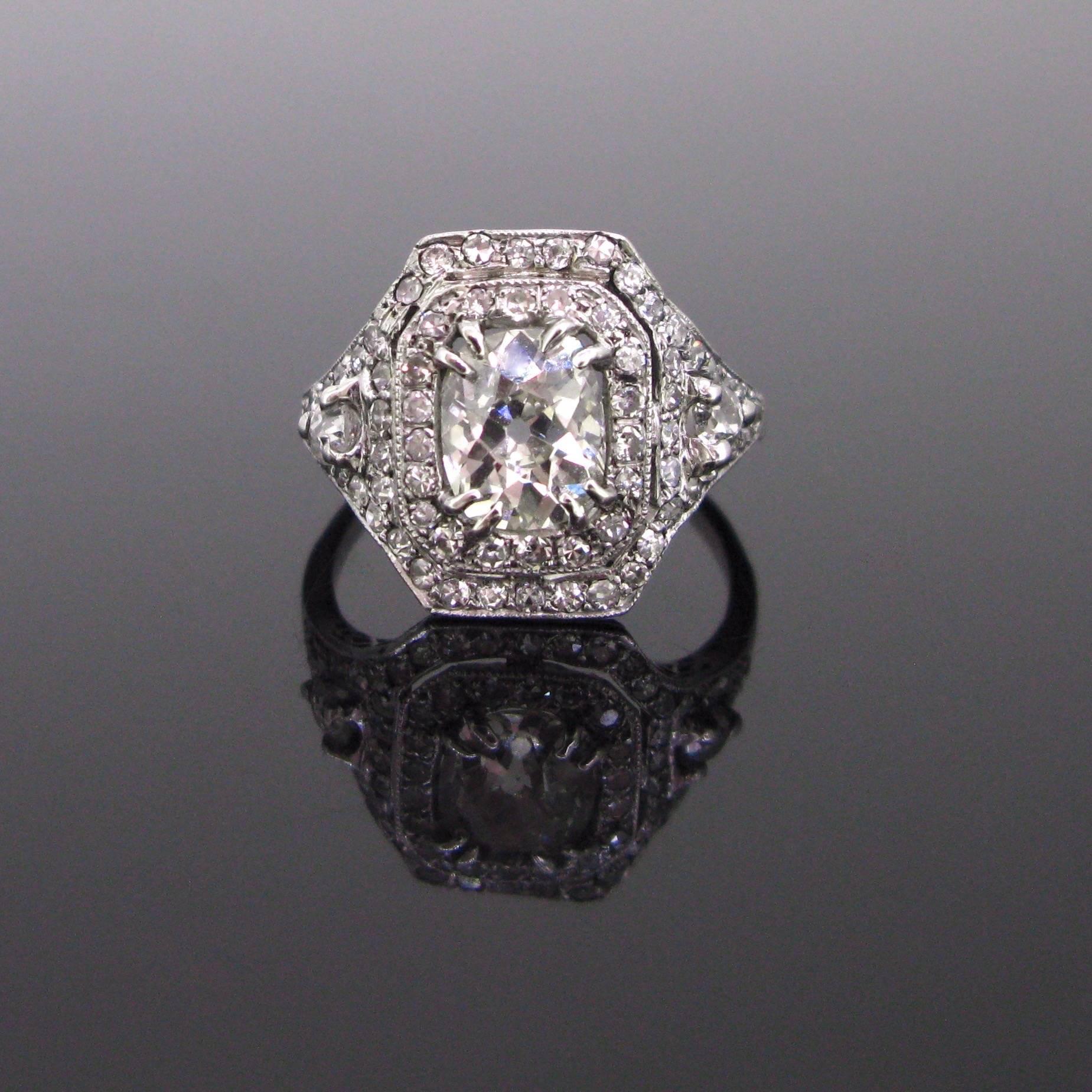 This beautiful ring is set with a vibrant rectangular cushion cut diamond. It is surrounded with 8/8 cut diamonds. The shoulders are adorned with diamonds, with a millegrain setting. It was fully handcrafted into platinum and hallmarked with the