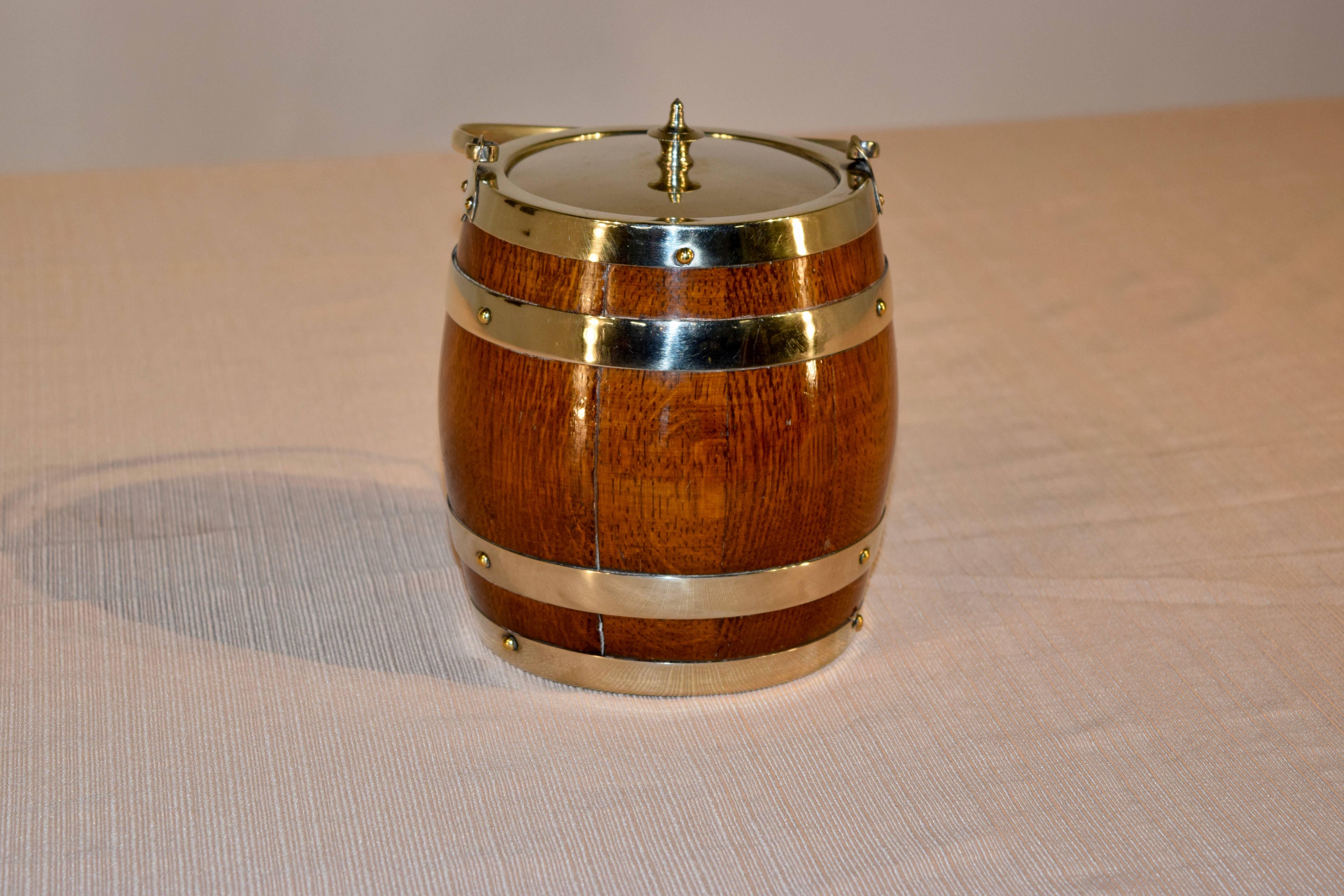 English oak biscuit barrel, circa 1900-1910. The handle, lid, barrel straps, and central shield are silver-plated, and the inner lining is made from porcelain.